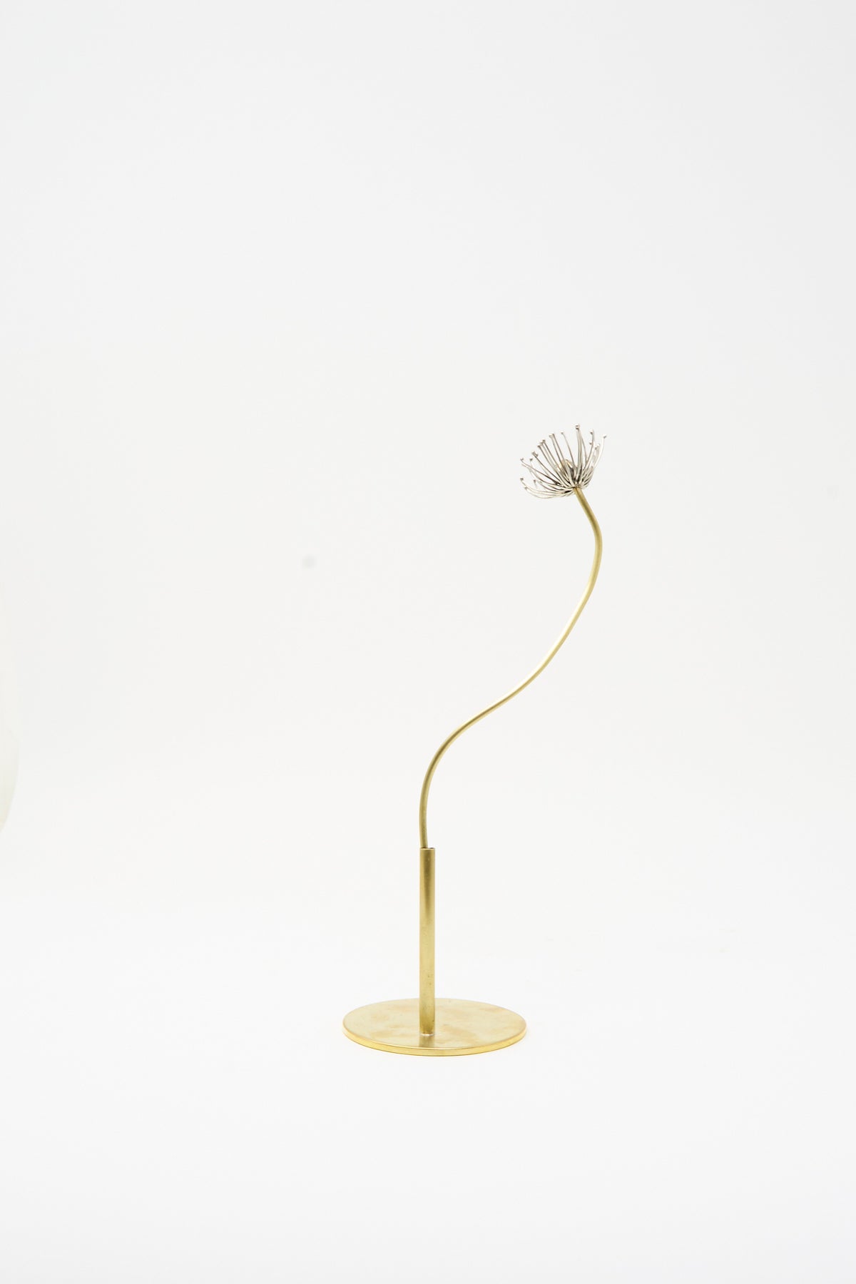 The Sterling Silver and Brass Papaver No. 11 is a metal sculpture of a flower with a thin, curved brass stem and a sterling silver seed head on a circular base.