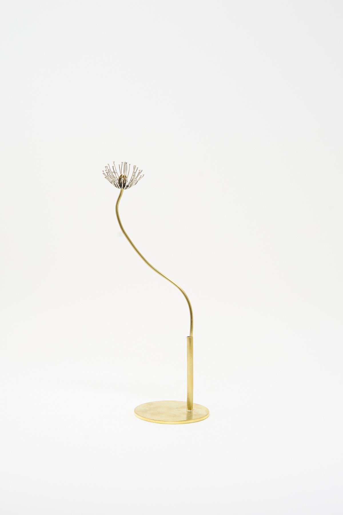 The Alison Layton Sterling Silver and Brass Papaver No. 11 sculpture features a thin, curved stem on a circular base topped by a silver, radial-patterned flower head.