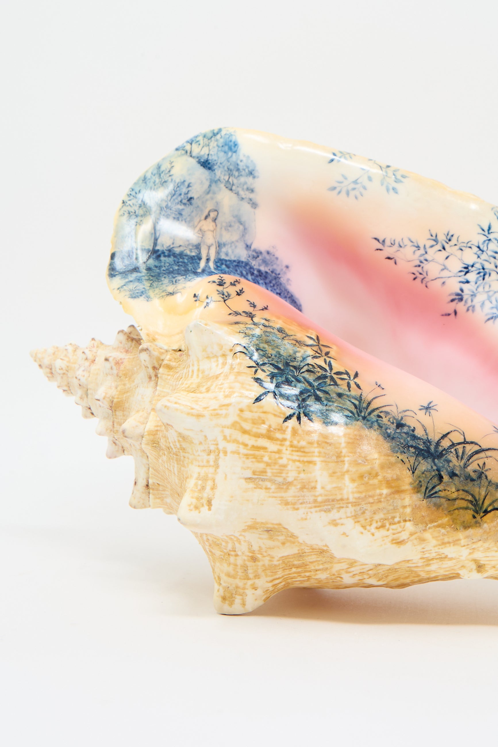 Introducing the Hand Painted Conch I from Alyssa Goodman, a stunning decorative conch shell that beautifully showcases hand-painted landscapes with trees and a small human figure. The design features pink and beige hues, enhanced by intricate blue watercolor detailing.