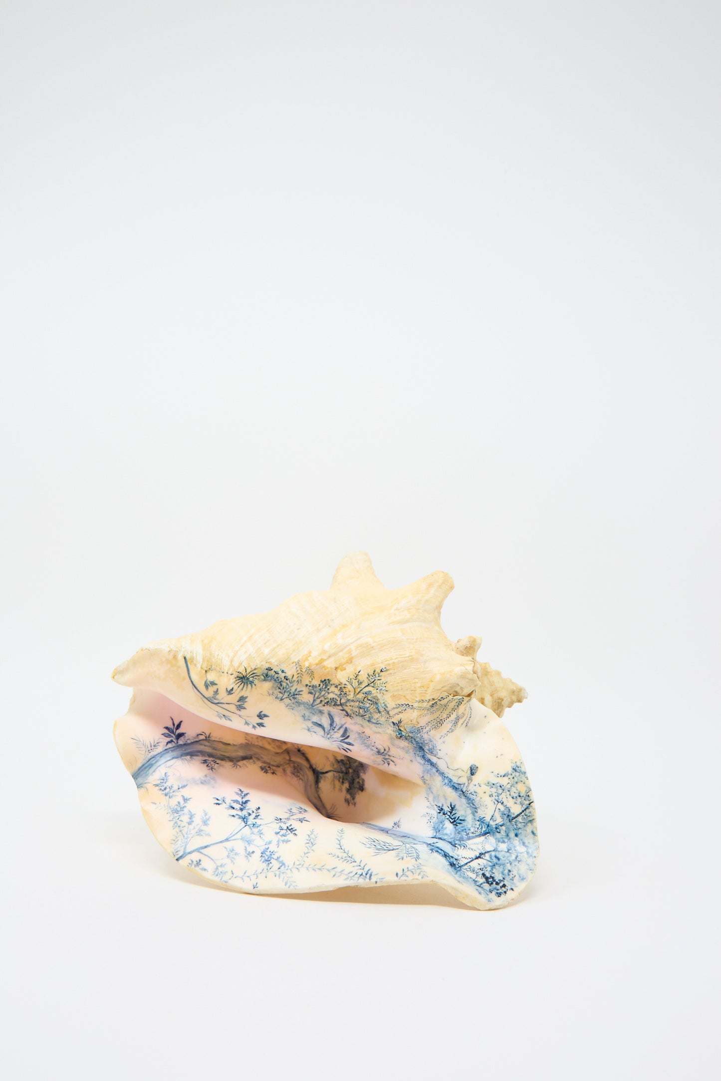 A Hand Painted Conch III from Alyssa Goodman, featuring intricate blue designs that depict trees and a landscape, showcasing hand-painted artistry.