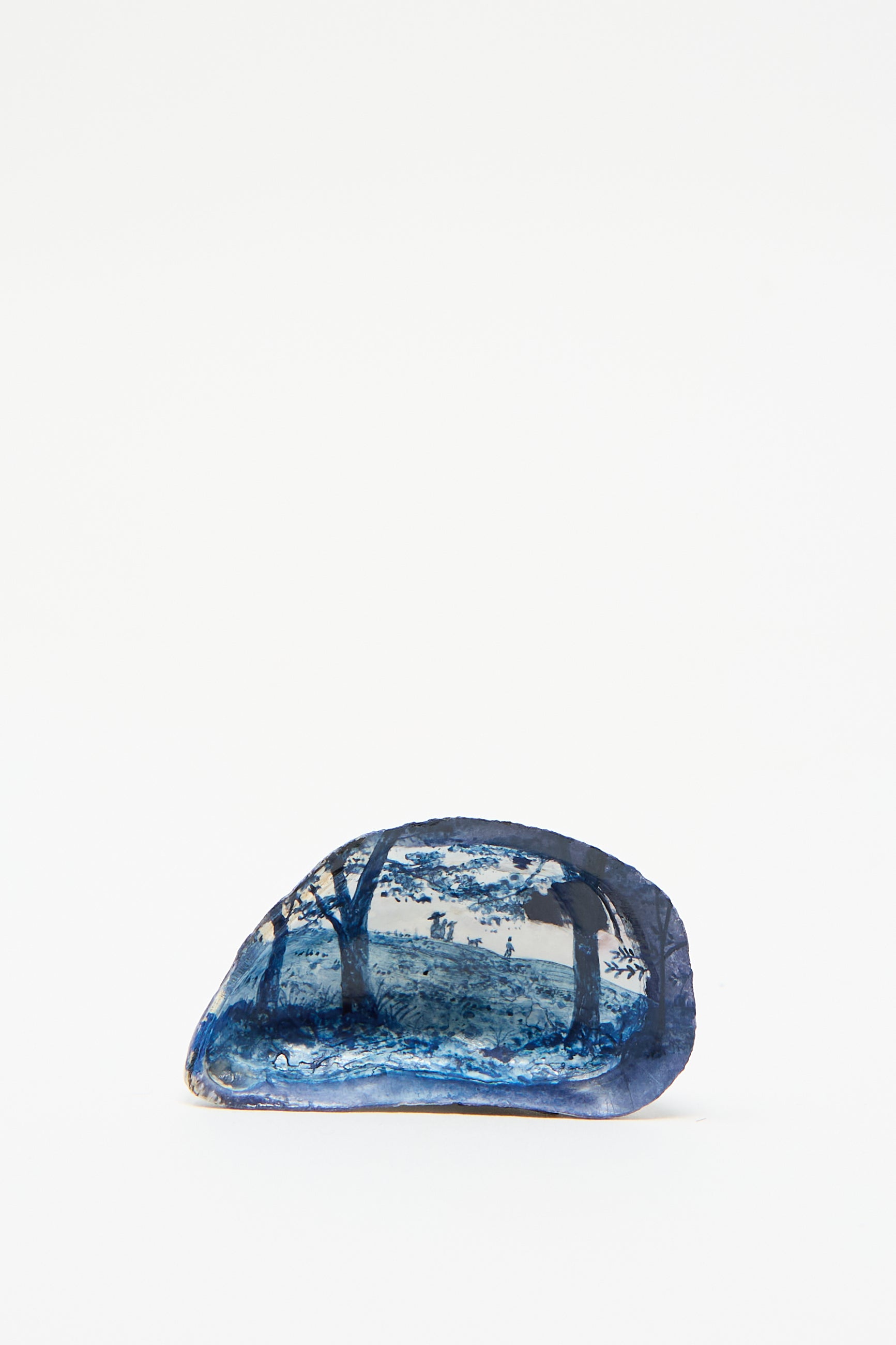 Hand Painted Family Shell by Alyssa Goodman: A blue polished stone featuring an intricate hand-painted landscape of a forest, complete with trees and people in the distance. 