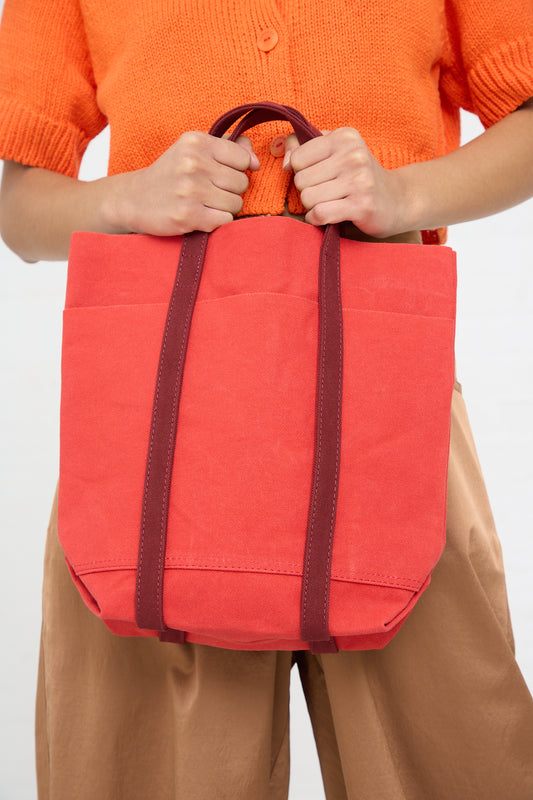 Person holding a red Light Ounce Canvas Tote in Scarlet and Burgundy with brown handles by Amiacalva.