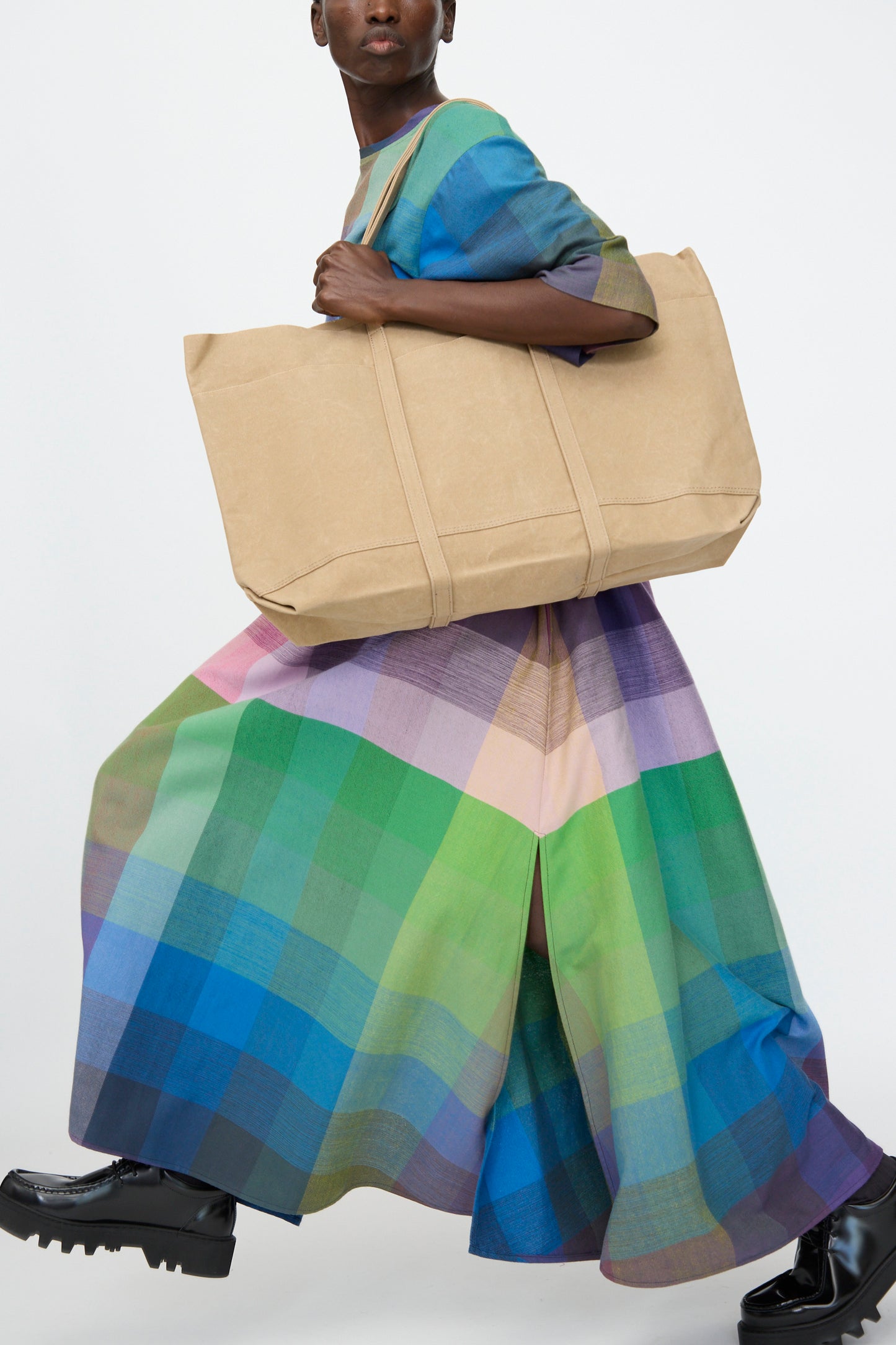 A person carries the Amiacalva Washed Canvas 6 Pockets Large Tote in Taupe against a plain background, styled with a colorful plaid dress and black shoes.