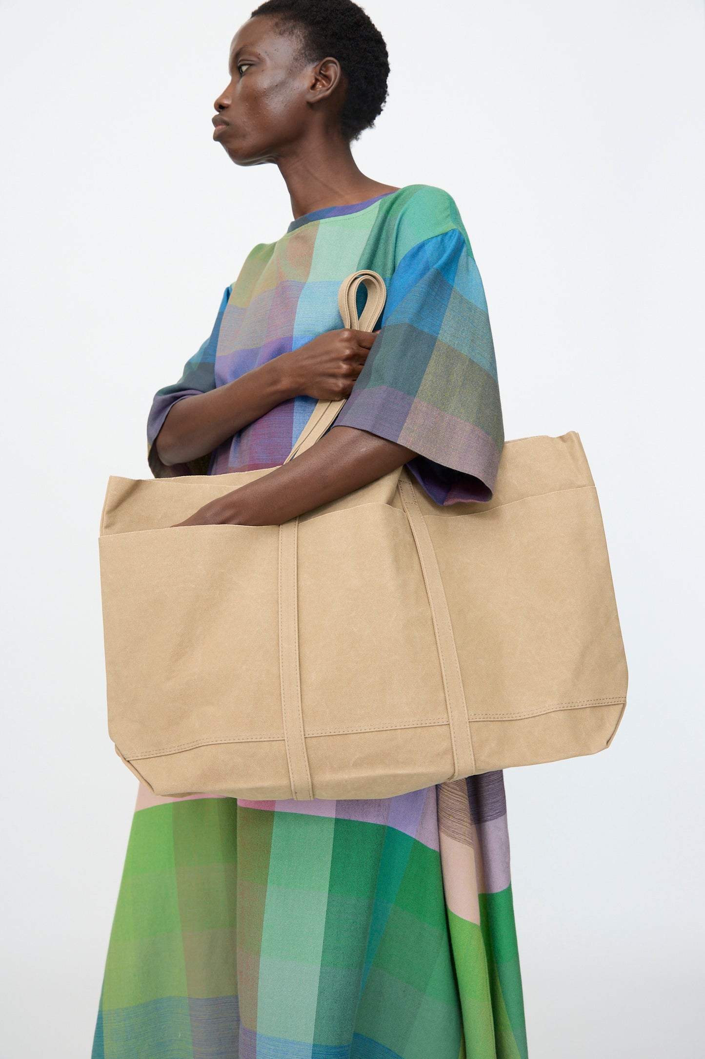 A person holds the Amiacalva Washed Canvas 6 Pockets Large Tote in Taupe against a plain white background.