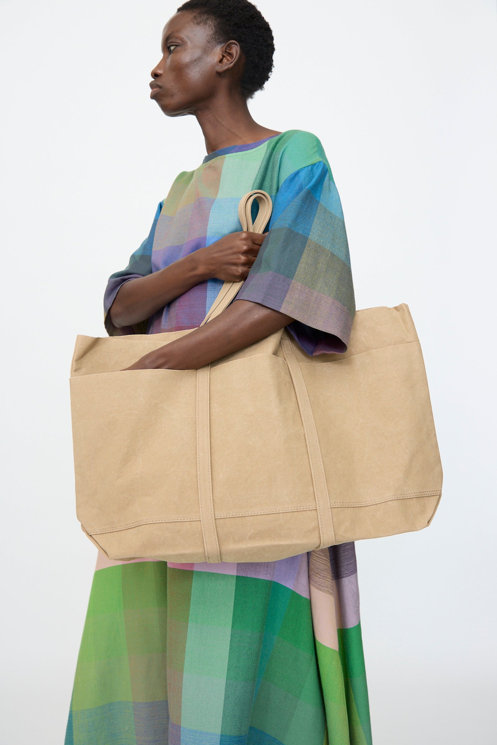A person holds the Amiacalva Washed Canvas 6 Pockets Large Tote in Taupe against a plain white background.