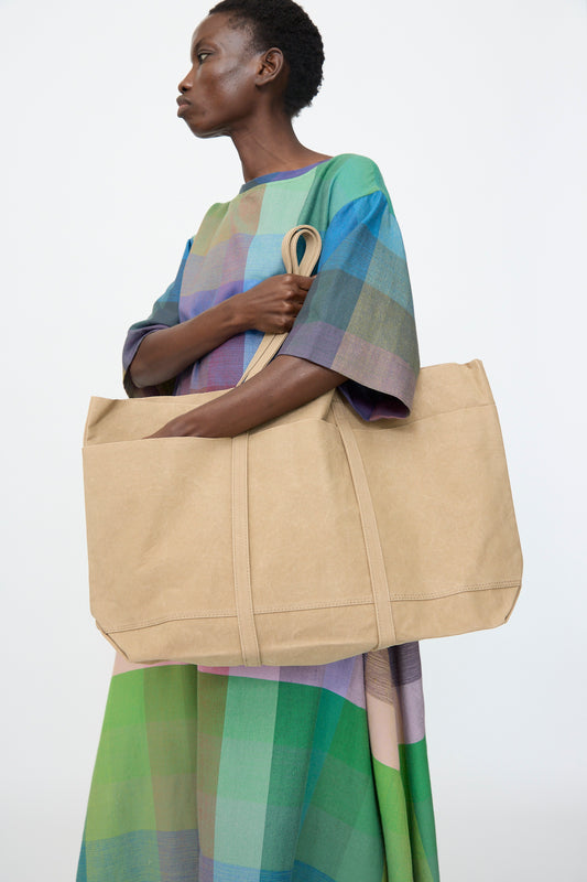 A person holds the Amiacalva Washed Canvas 6 Pockets Large Tote in Taupe against a plain white background.