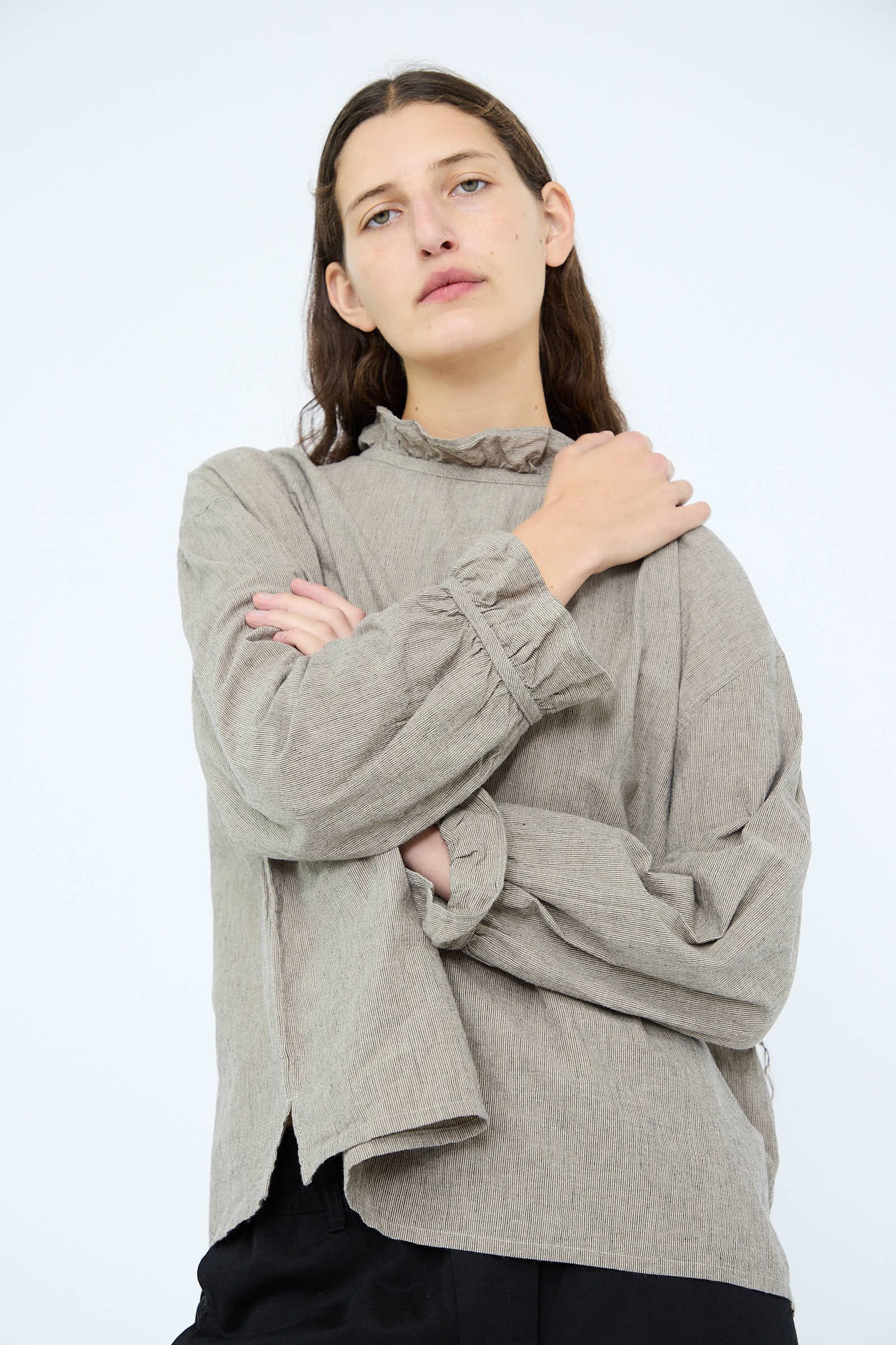 A person with long brown hair is wearing an Antiquités Noir Cotton Linen Two Way Frill Blouse in Stripe, standing against a plain white background.