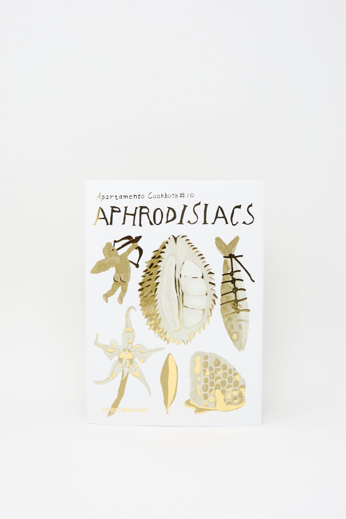 Cover of the Apartamento Cookbook #10: Aphrodisiacs, featuring gold and beige illustrations of a cherub, durian, fish, flower, leaf, and honeycomb.