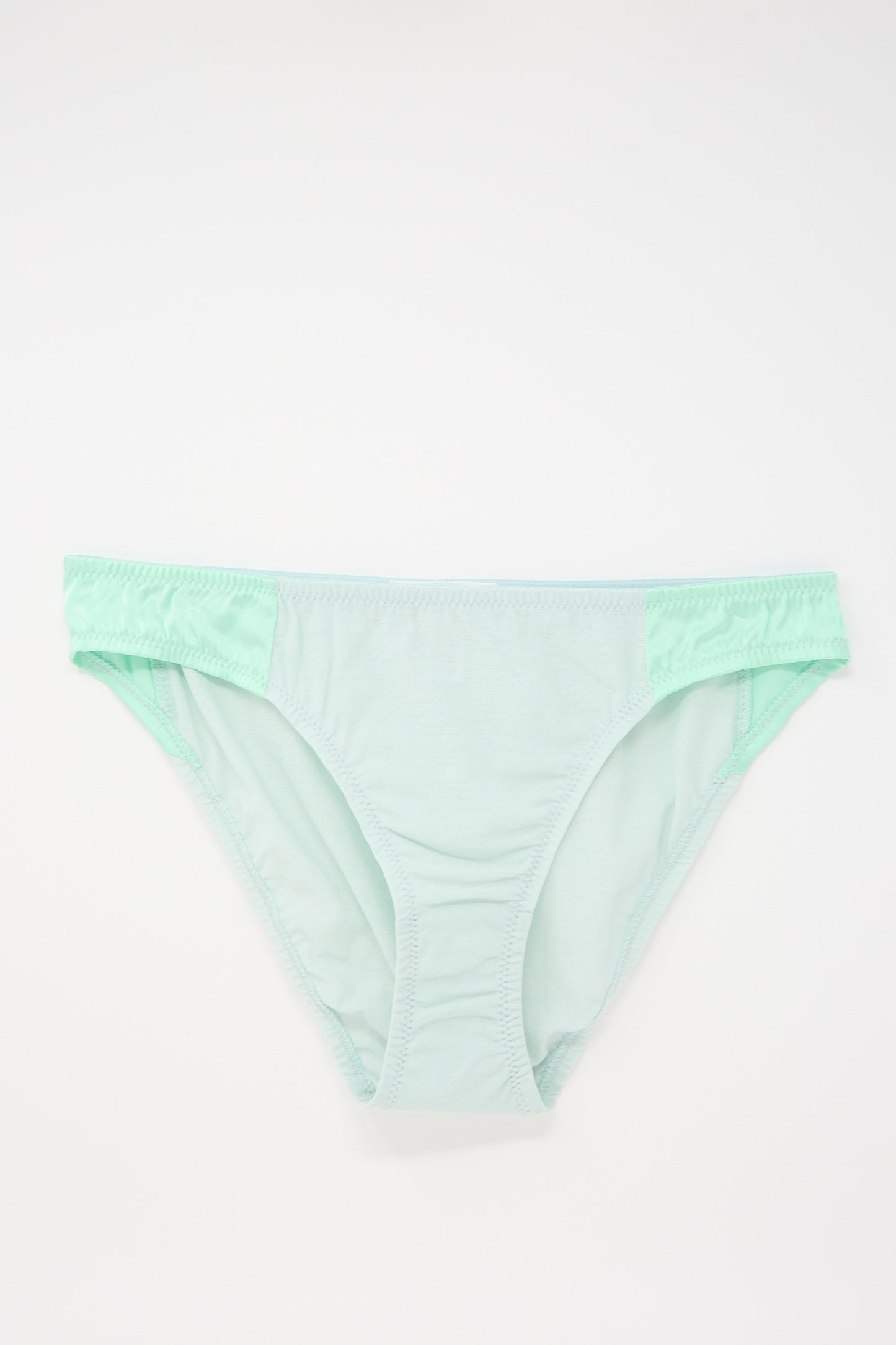 A pair of light green, mid-rise panty underwear displayed on a white background.
The Saffi Panty in Cloud by Araks is featured on a white background.