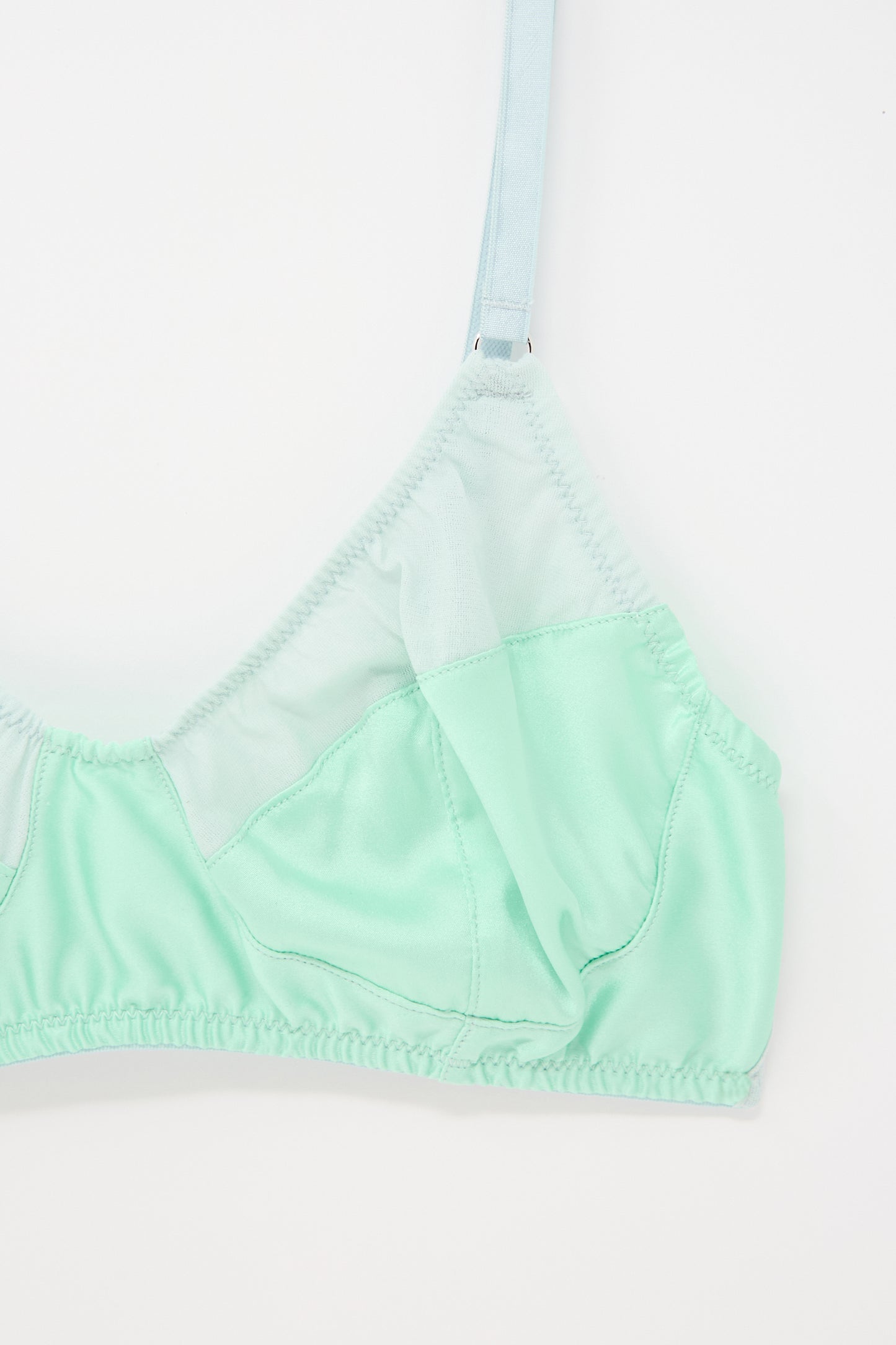 A close-up view of the Willow Bralette in Cloud by Araks with thin straps and a mesh overlay, photographed against a white background.