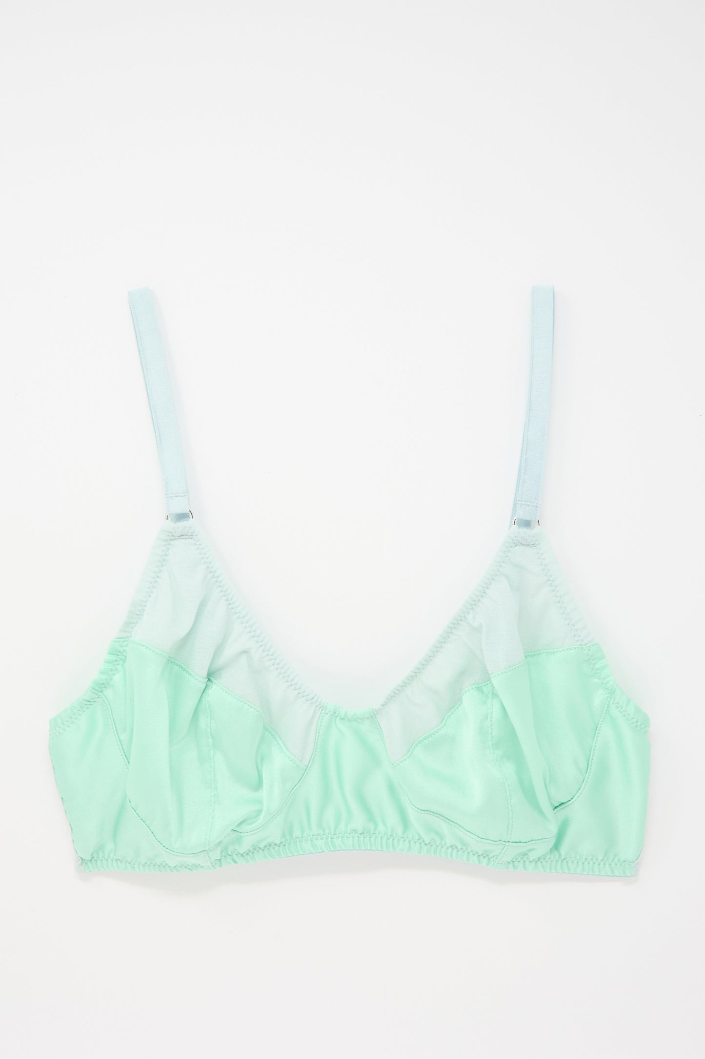 A light green Willow Bralette in Cloud with adjustable straps, featuring mesh and satin fabric details by Araks, laid flat on a white background. Its full coverage design ensures both comfort and support.