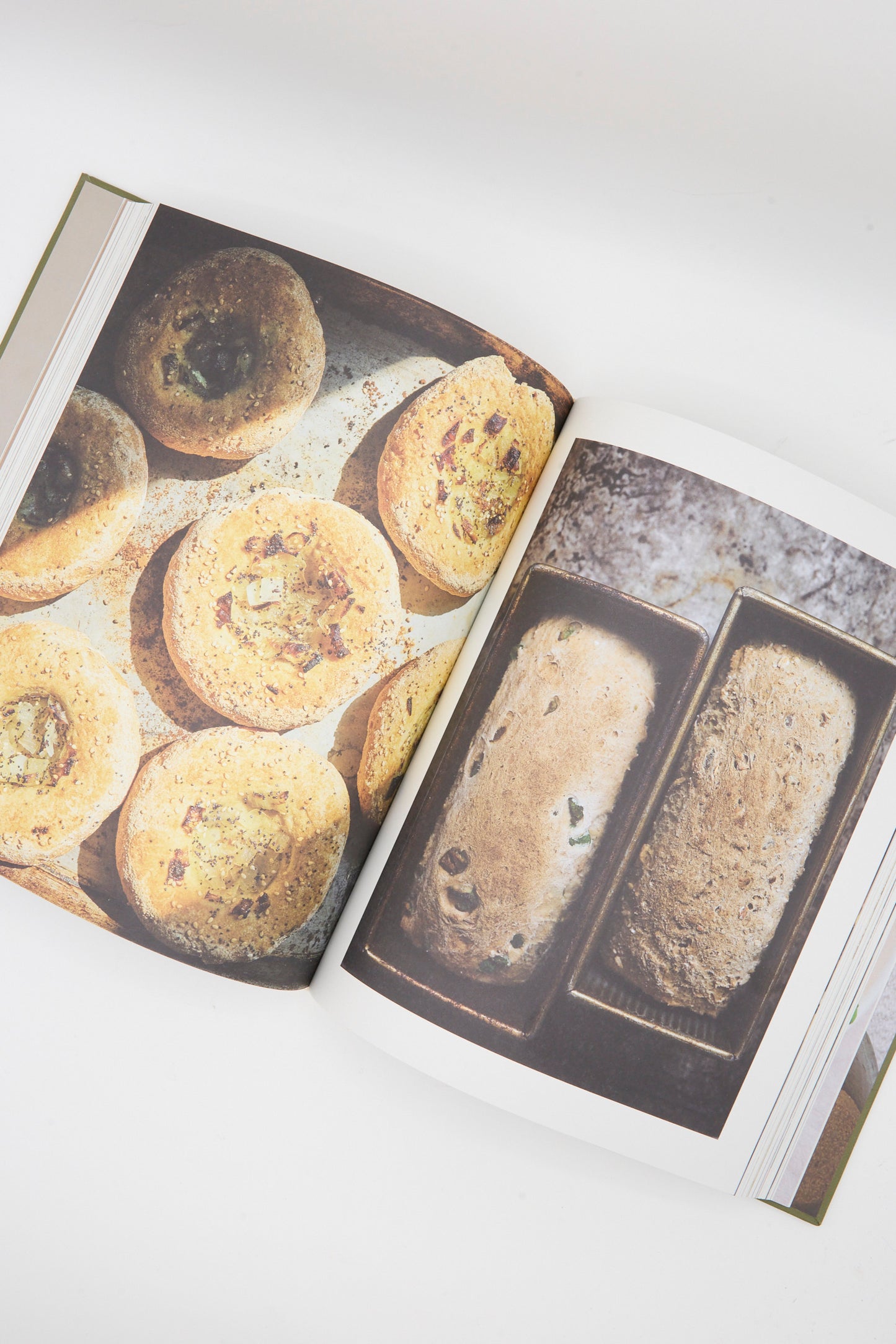 Open cookbook displaying photos: savory muffins on the left and two gluten-free bread loaves from "The Art of Gluten-Free Bread" by Aran Goyoaga in pans on the right.