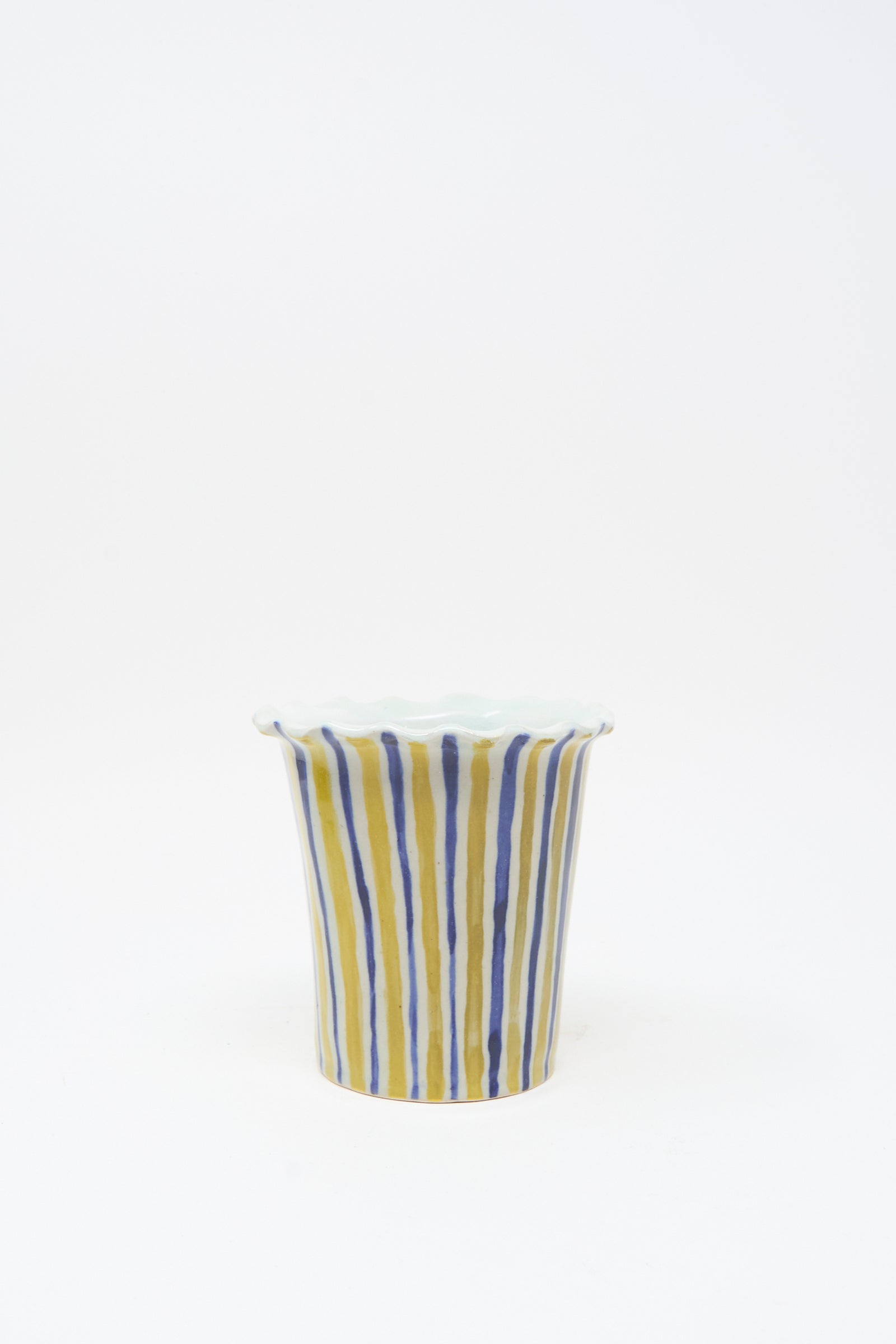 The Hand Painted Bird Vessel by Ariel Clute is a handmade porcelain cup with an uneven rim, featuring vertical blue and yellow stripes on a white background.