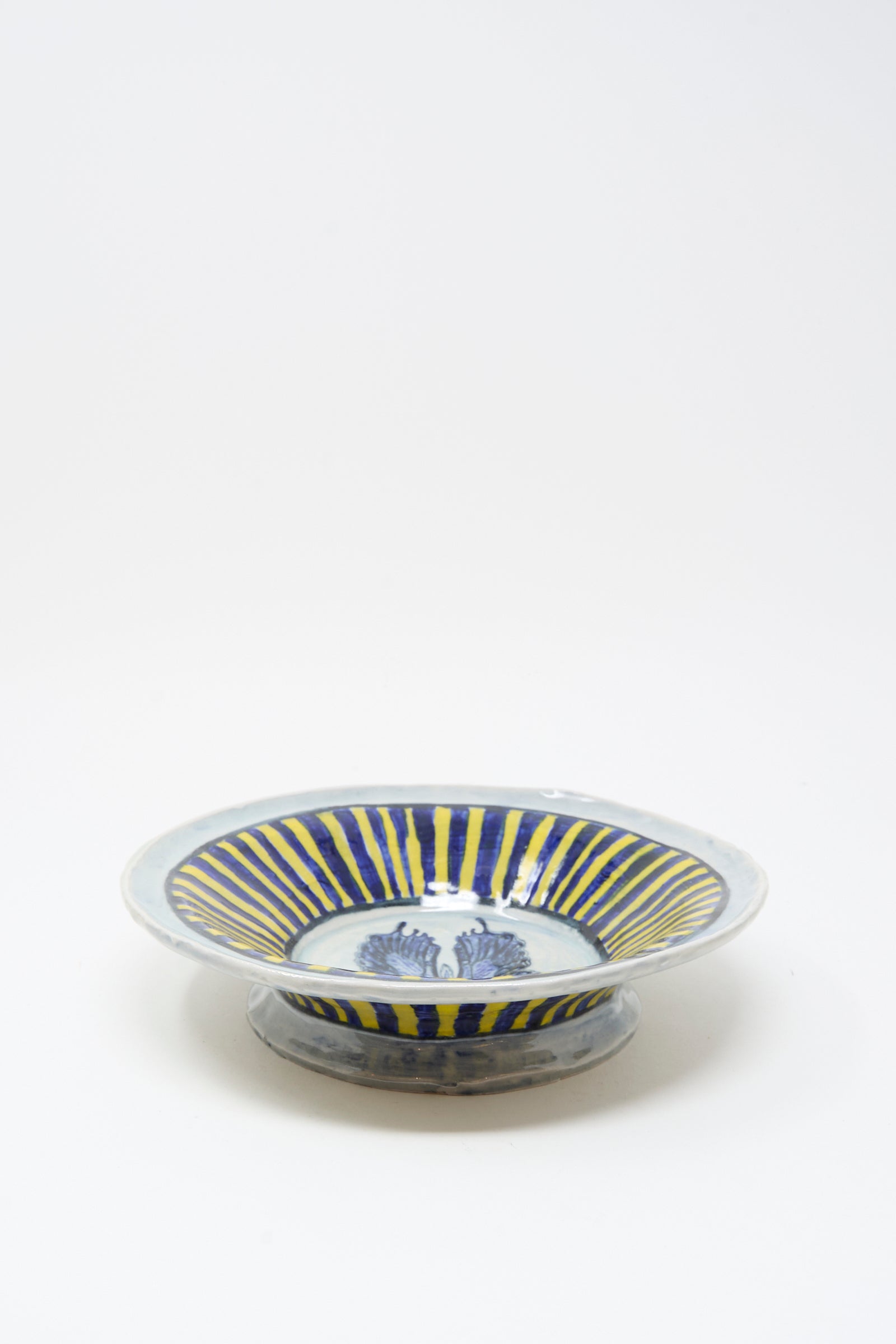 The Ariel Clute Hand Painted Butterfly Bowl features blue and yellow radial stripes and a blue central pattern on porcelain, handmade in California, shown against a plain white background.