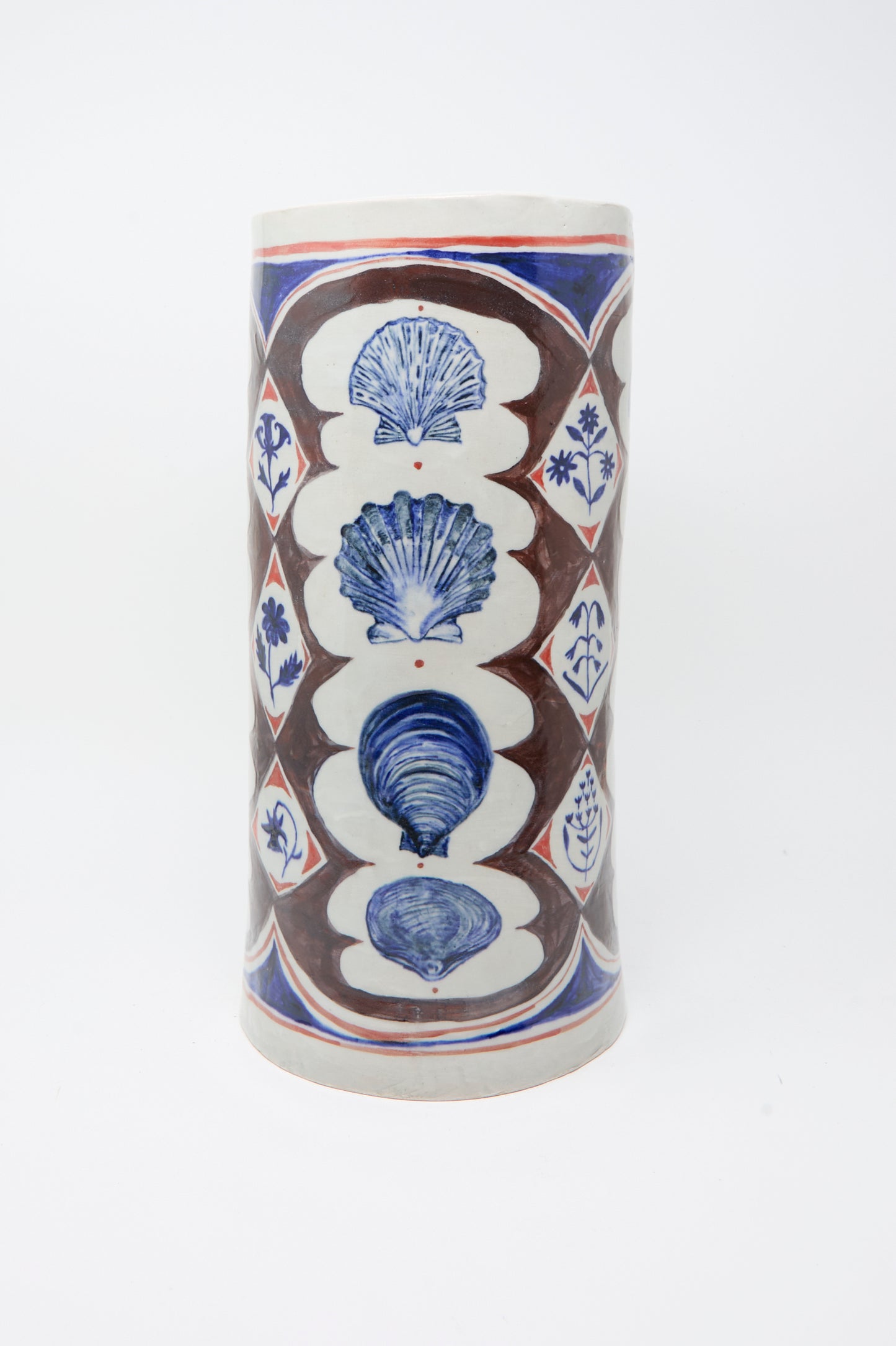 The Sea Shore Vessel by Ariel Clute is a tall, hand-painted porcelain piece with shell motifs and geometric floral patterns in brown, blue, and red on a white background.