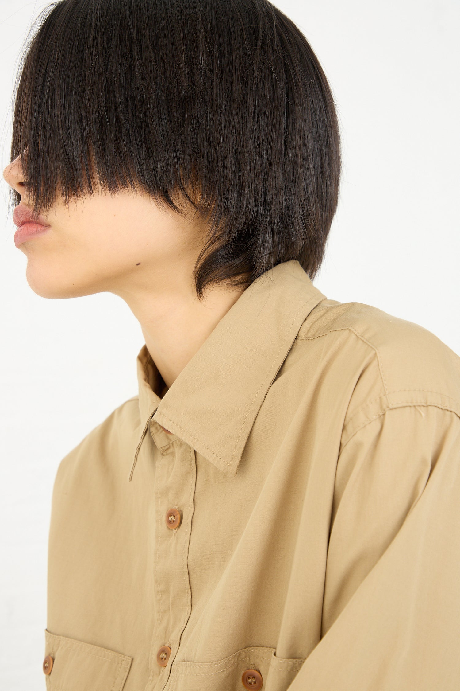 Profile of a person with a bob haircut wearing an As Ever 101 Shirt in 40's Khaki button-down collared shirt.