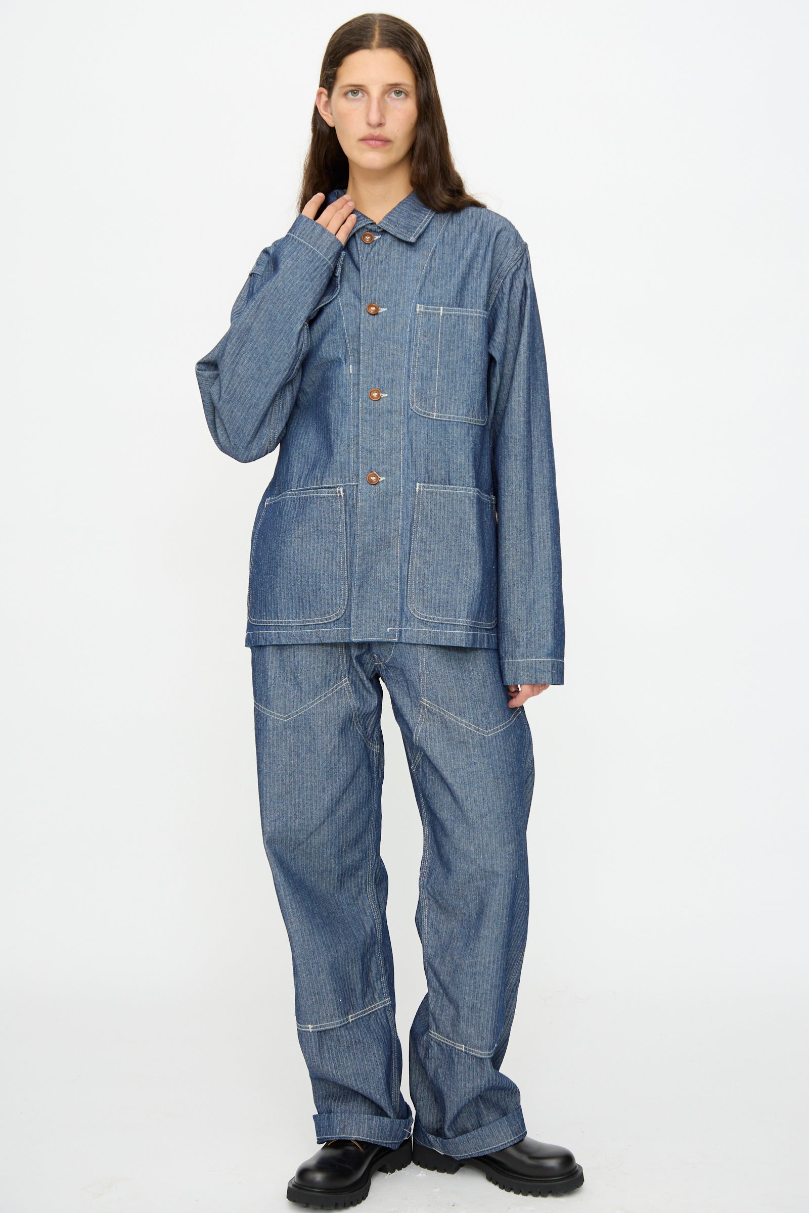 A person stands against a white background, wearing the As Ever Henri Jacket in blue HBT denim with matching pants and black shoes.