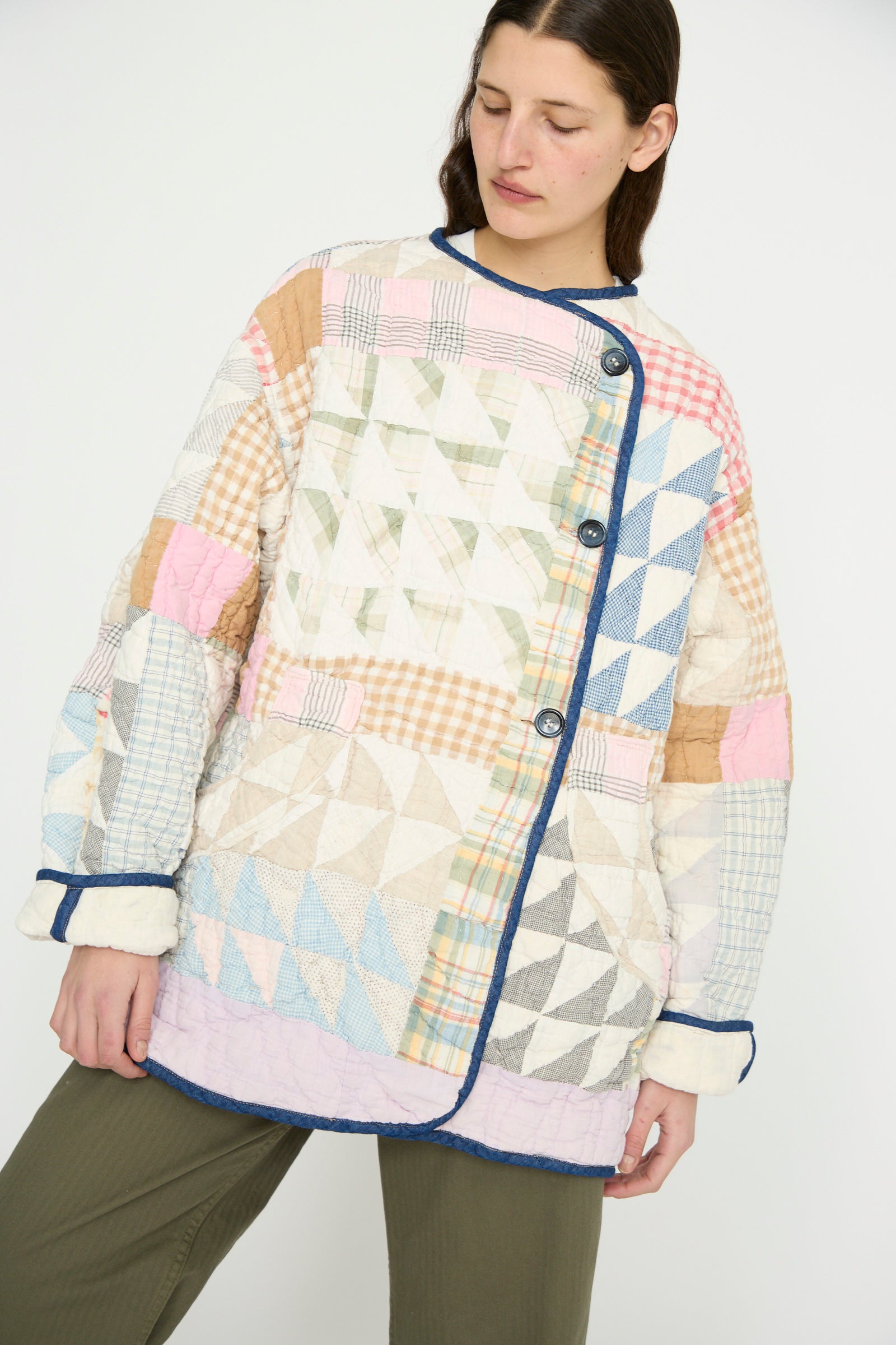 A model wearing the Vintage Quilt Coat in Multi Color by As Ever, paired with olive green pants, against a plain backdrop.