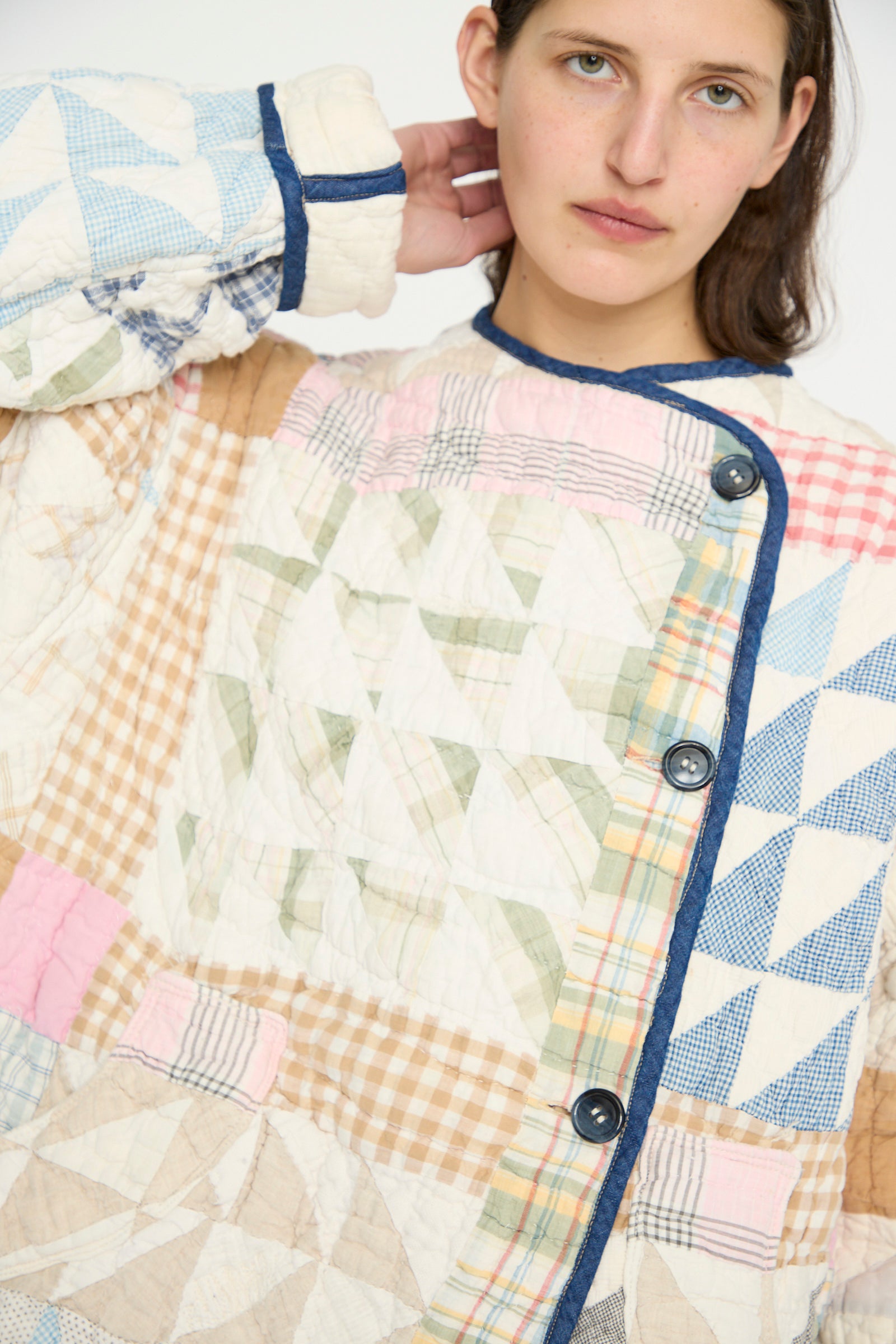 A person is wearing the As Ever Vintage Quilt Coat in Multi Color, featuring reversible quilted vintage cotton with geometric patterns, patchwork design, and button details.