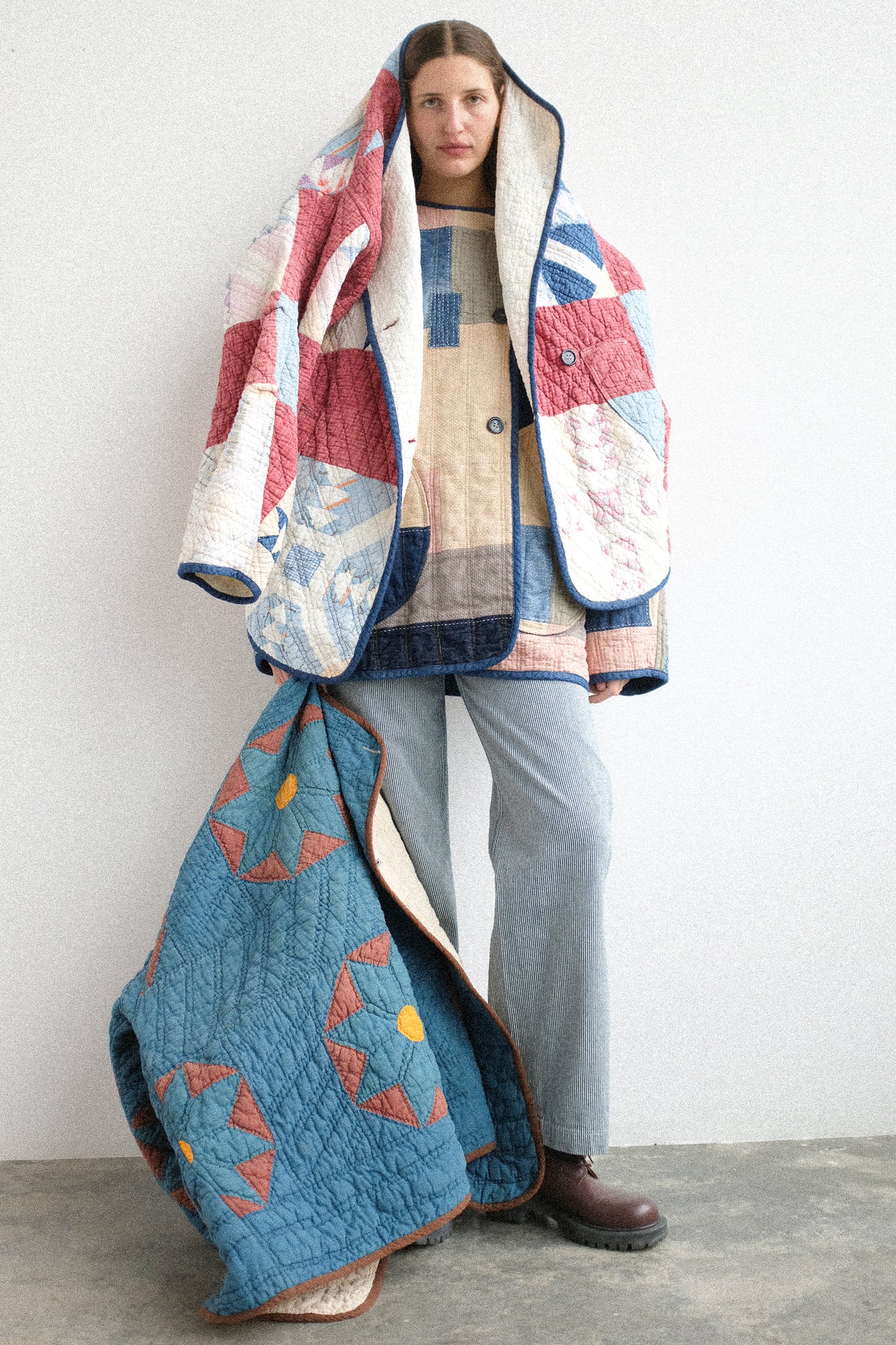 A woman wearing the As Ever Vintage Quilt coats on her body and over her head, against a white background.