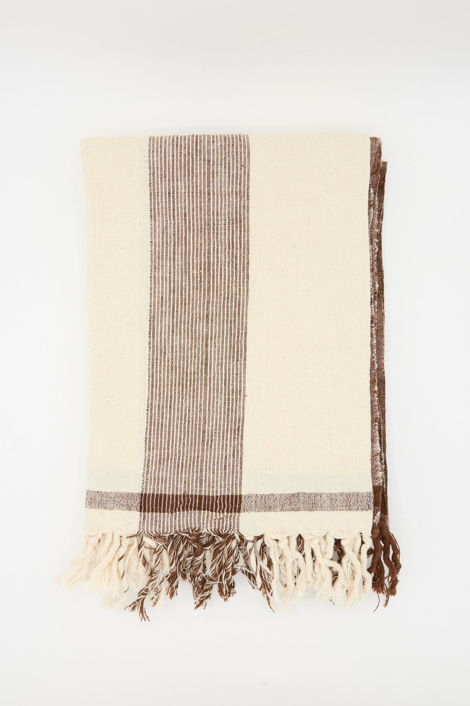 The Auntie Oti Cotton Khadi Natural Dye Towel in Brown Stripe features cream-colored cotton with brown stripes and fringed edges, displayed on a plain white background.