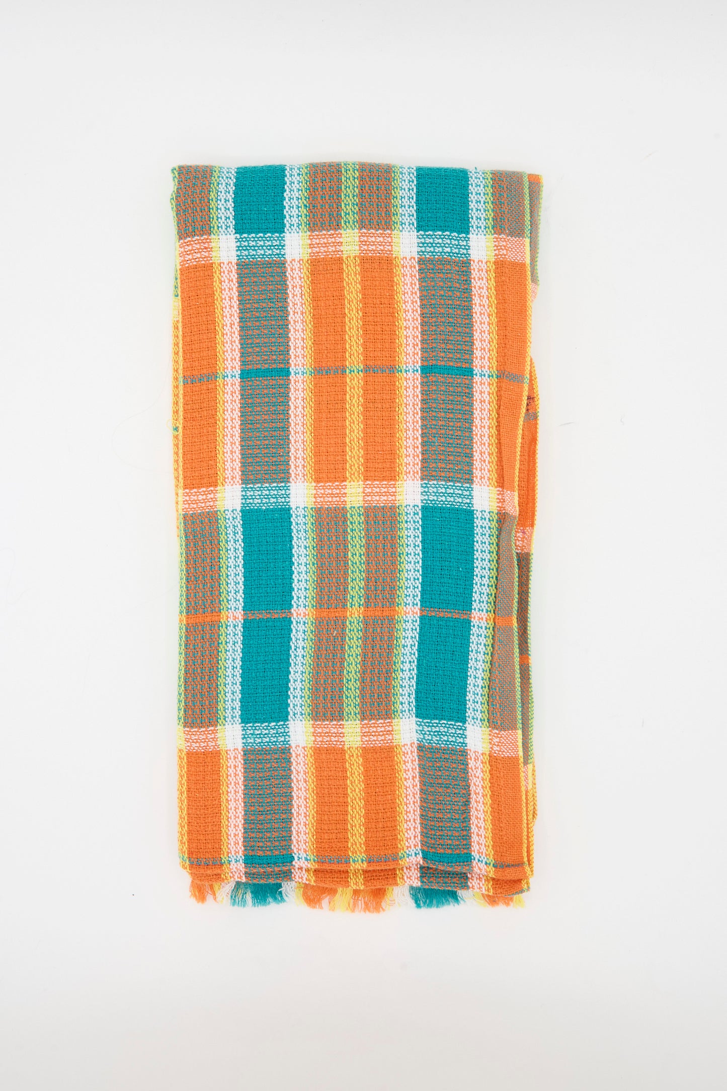 The Auntie Oti Dobby Plaid Towel in Orange and Green is a handwoven rectangular kitchen towel with short tasseled edges and a check plaid pattern, shown folded against a plain white background.