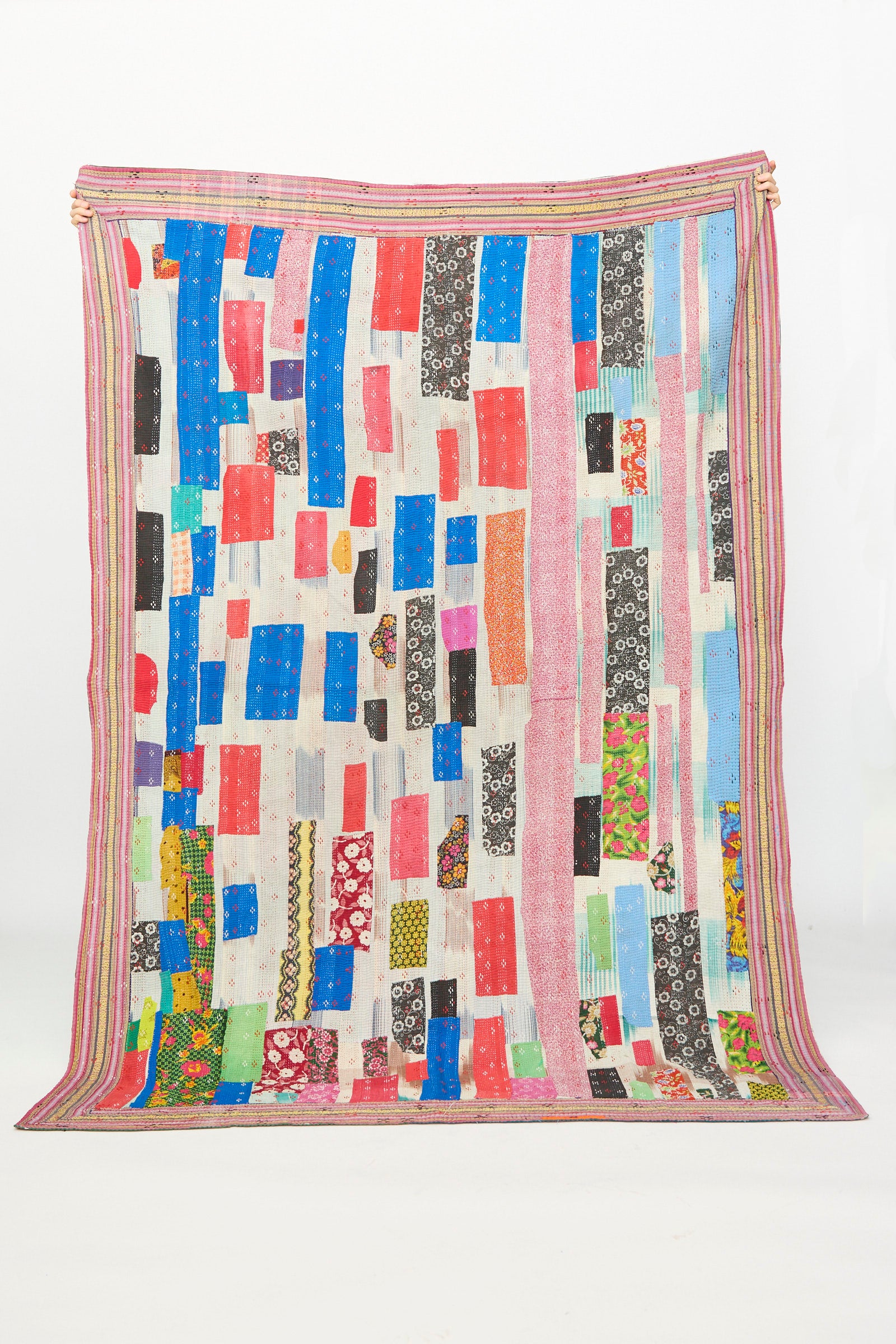 The One of a Kind Vintage Kantha Quilt IV by Auntie Oti features vibrant vertical stripes and patchwork rectangles in assorted colors and patterns, finished with pink and multicolored borders—a cozy, upcycled cotton quilt.