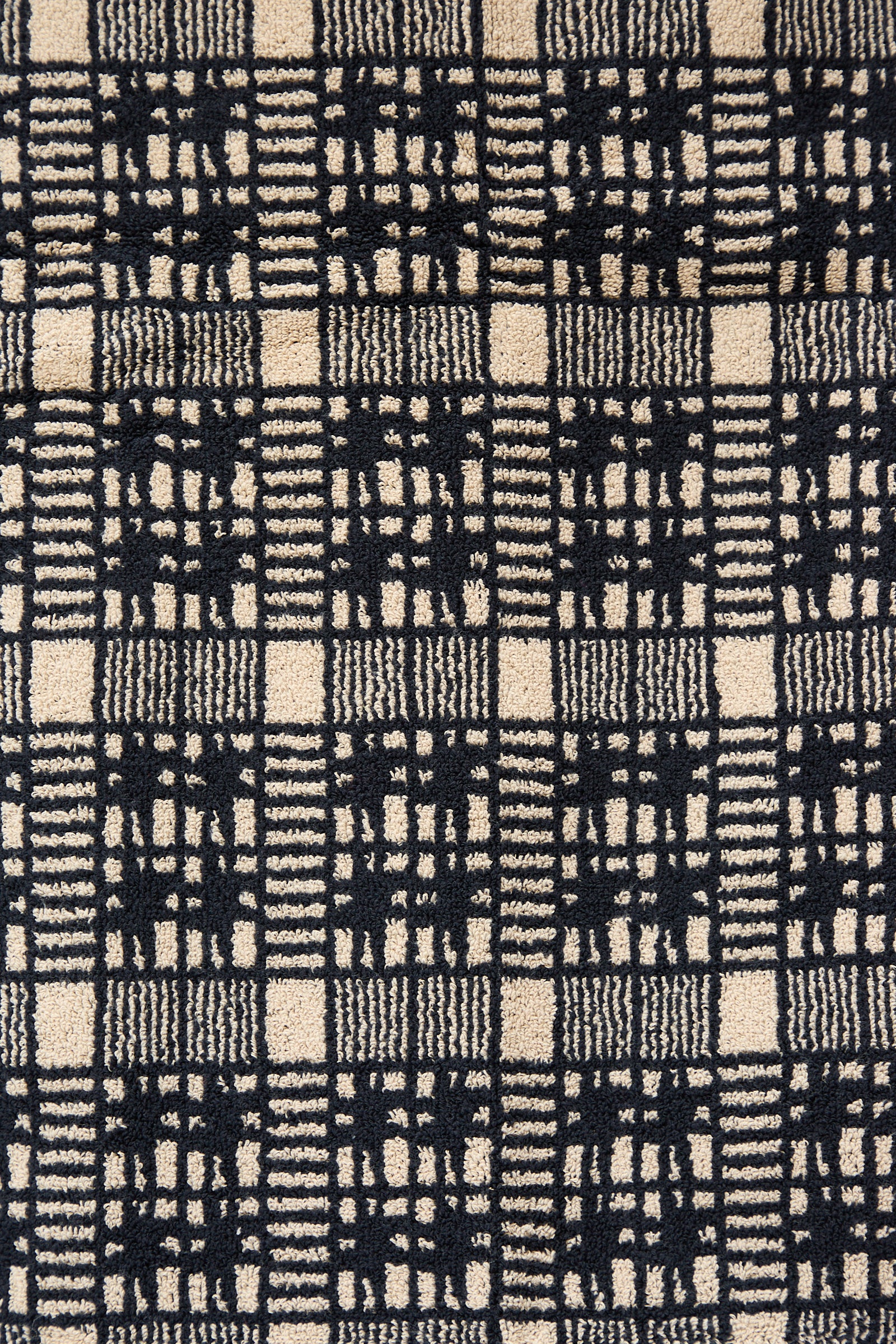 Close-up view of an Autumn Sonata Alma Bath Towel with a black and white checkered pattern, made in Portugal.