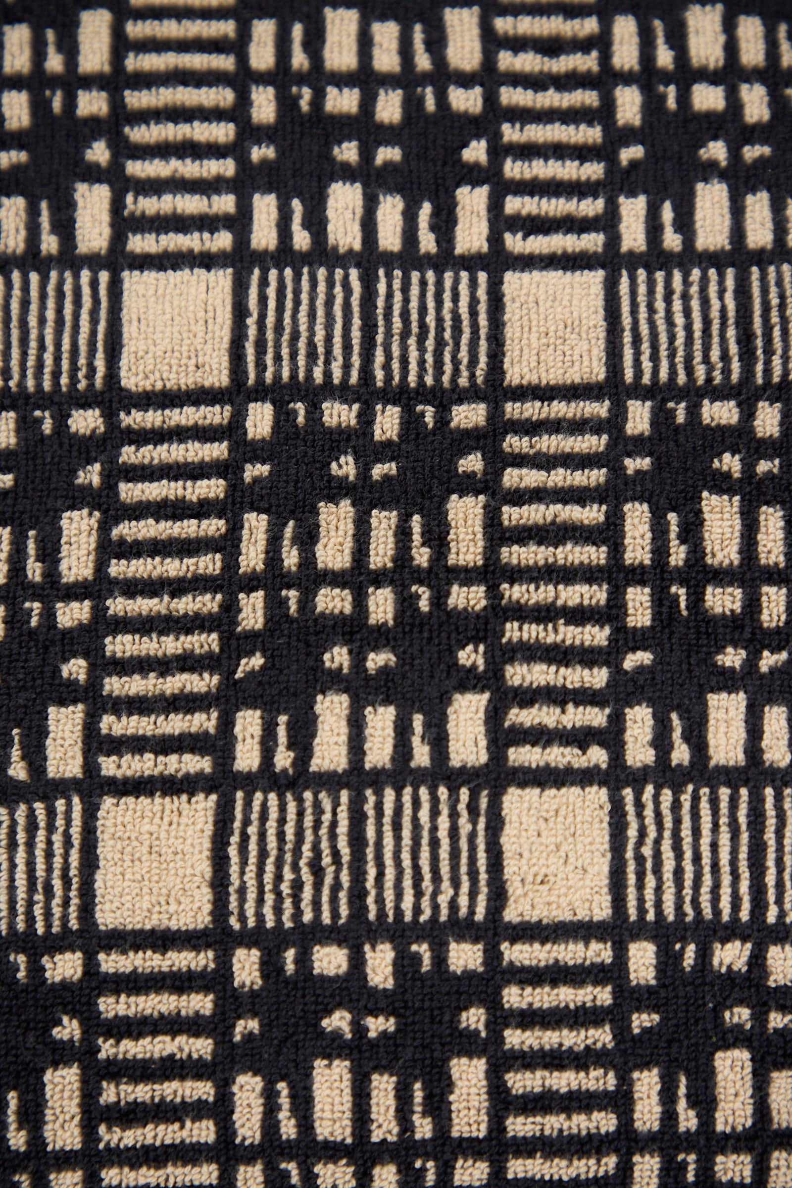 Close-up of the Alma Hand Towel by Autumn Sonata, showcasing its beige and black checkered design with vertical and horizontal lines of varying thickness, crafted from organic cotton.
