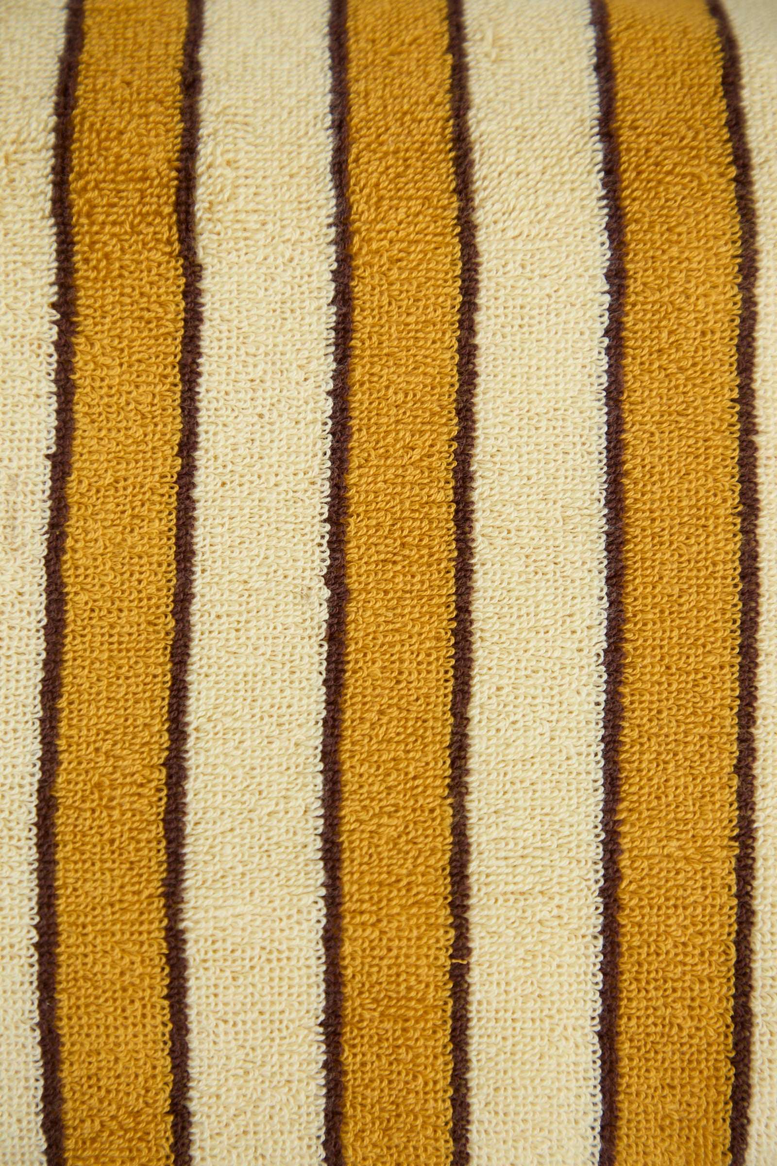 A close-up of the Helena Pool Towel in Ochre by Autumn Sonata, featuring a textured pattern with alternating vertical stripes in mustard yellow, cream, and brown, inspired by traditional Edo textiles and crafted from soft organic cotton.