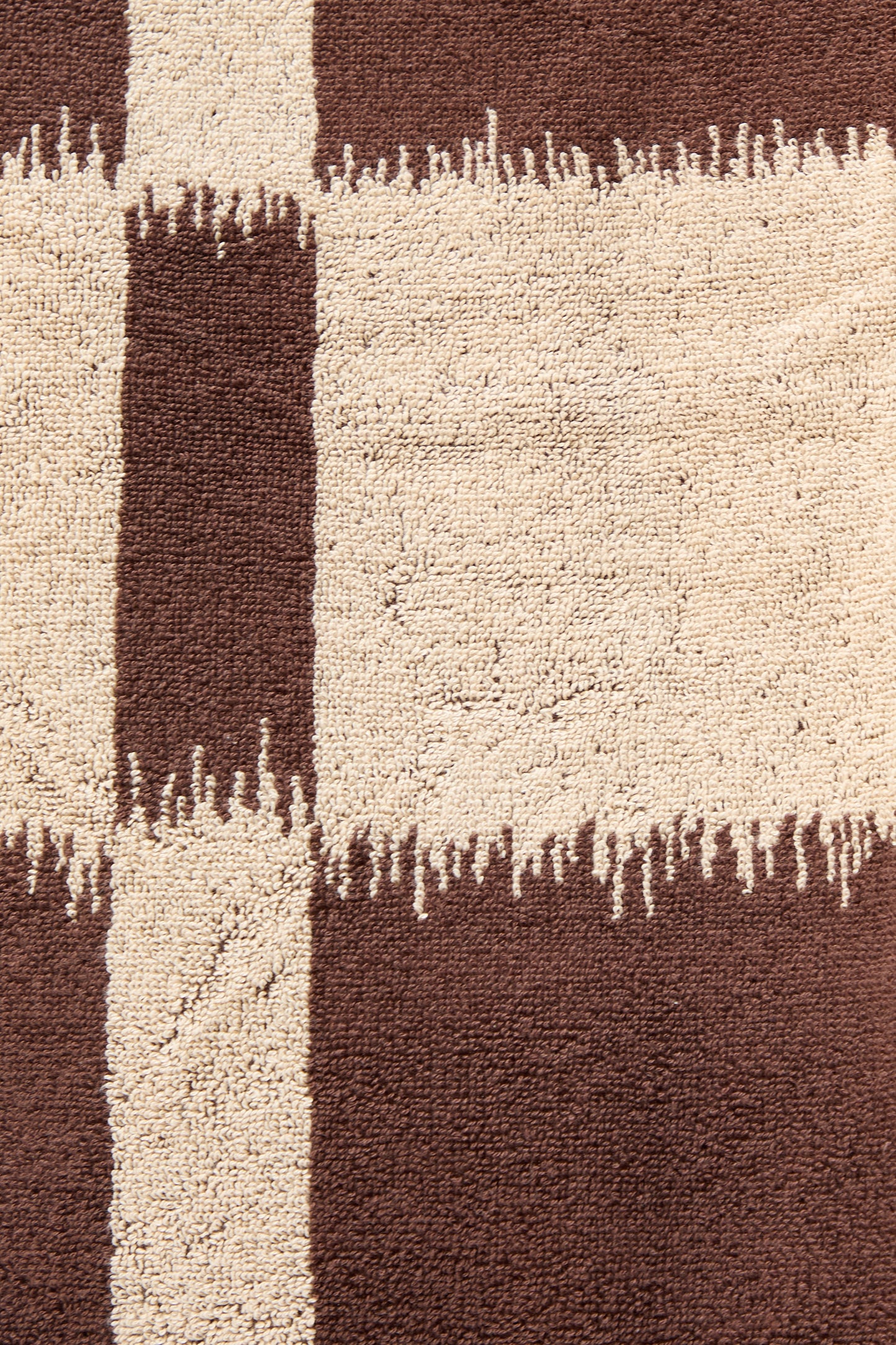 Close-up of a textured fabric with abstract Ikat weaving patterns in brown and cream, like the Autumn Sonata Karin Hand Towel.