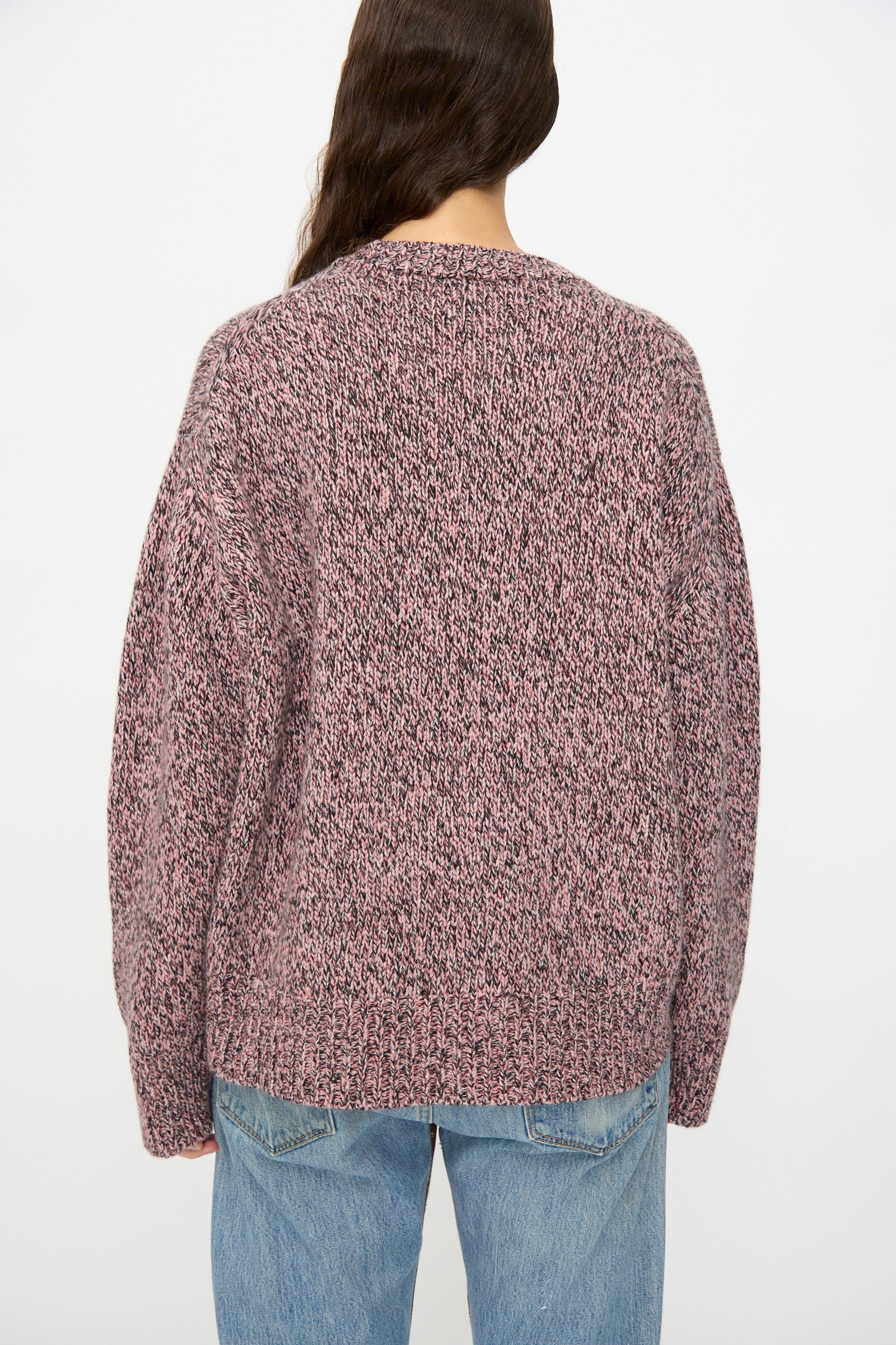 Model wearing the B Sides Braided Lambswool Crew in Etowah Twist, a marled pink and gray sweater, paired with blue jeans, shown from the back against a plain white background.