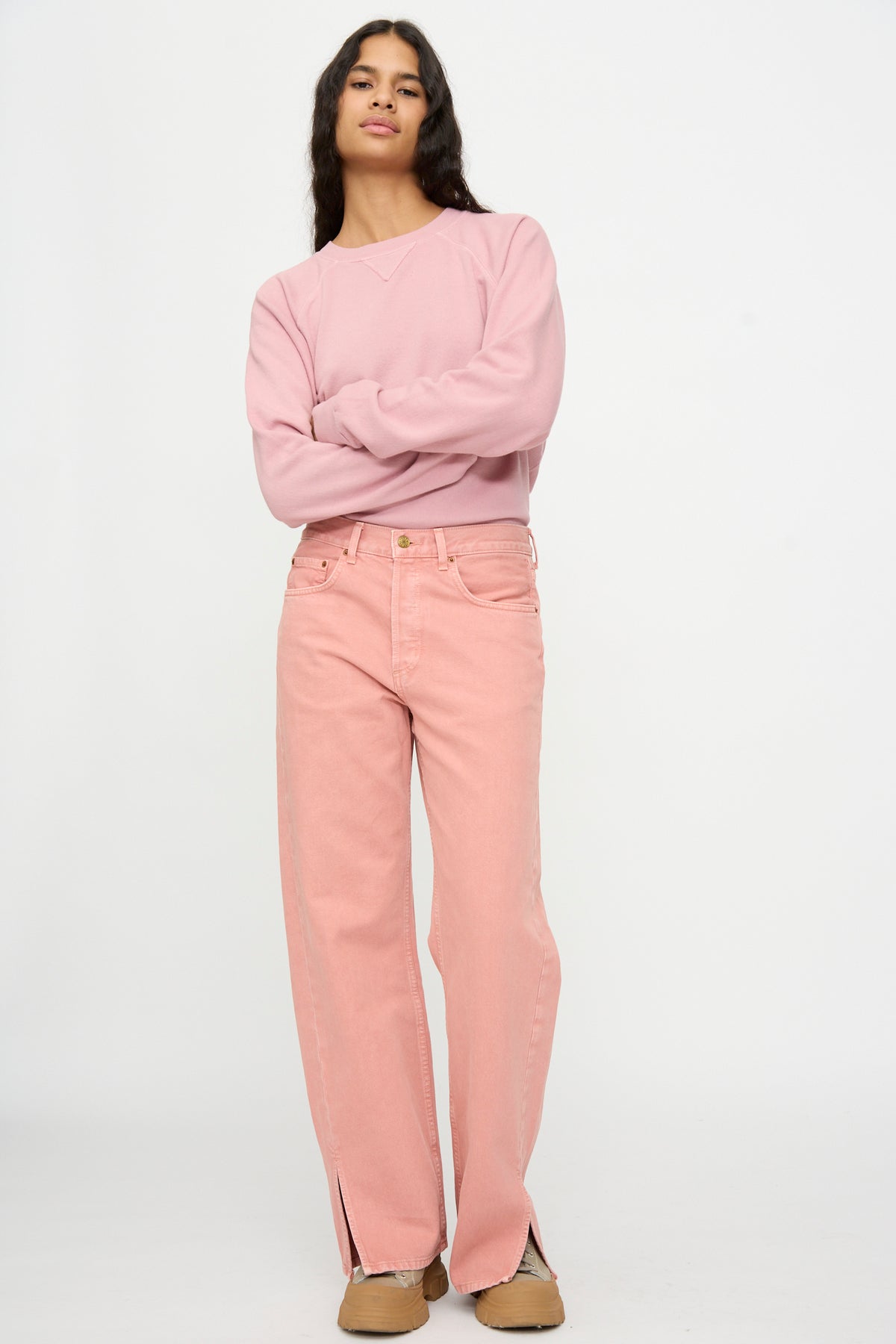 Person standing against a plain background, wearing a light pink sweatshirt, Charlot Split Hem in Myra Pink Overdye by B Sides, and tan shoes.