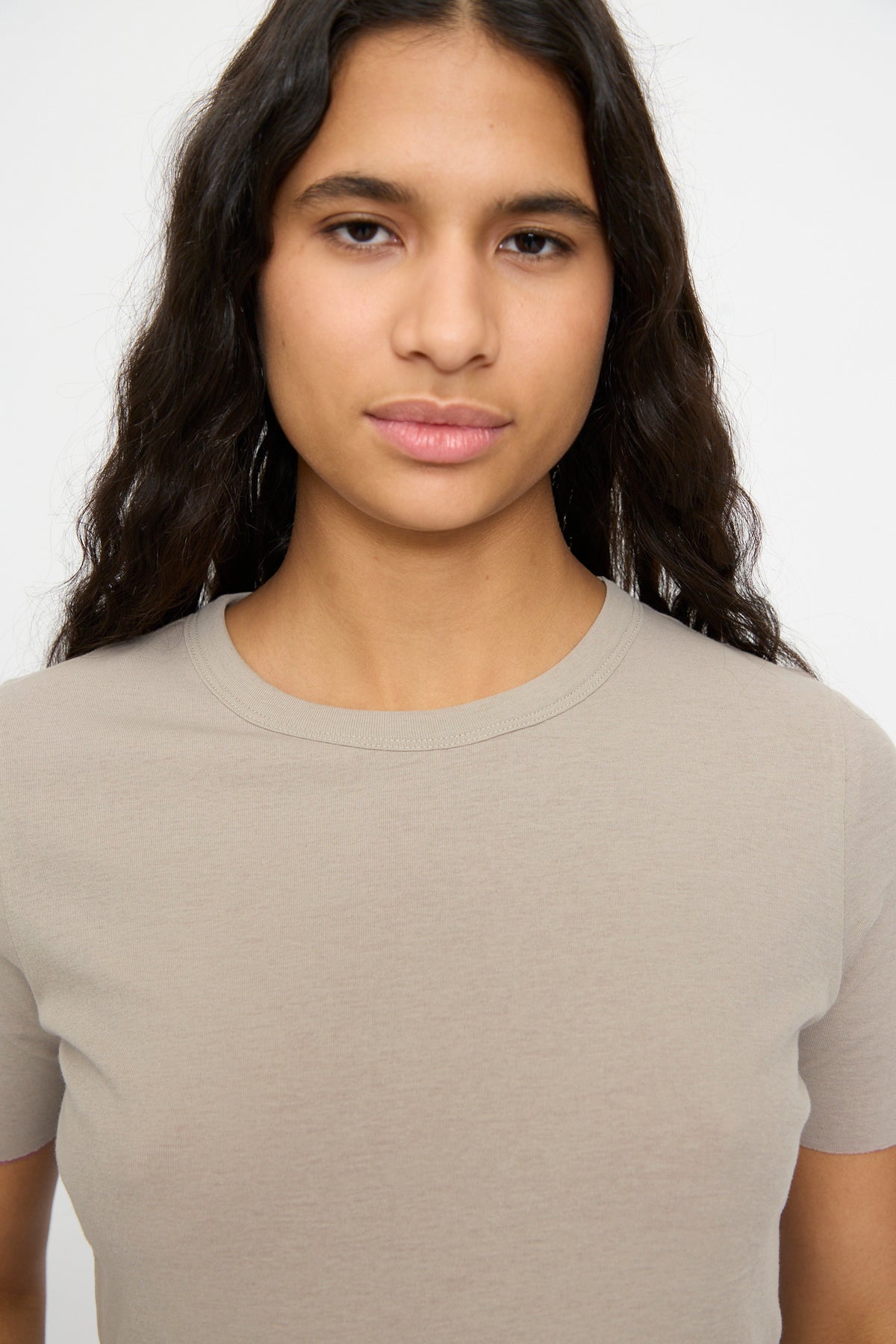 A person with long, dark wavy hair wears the Double Tee in Pink and Dove Grey by B Sides, standing against a plain white background.