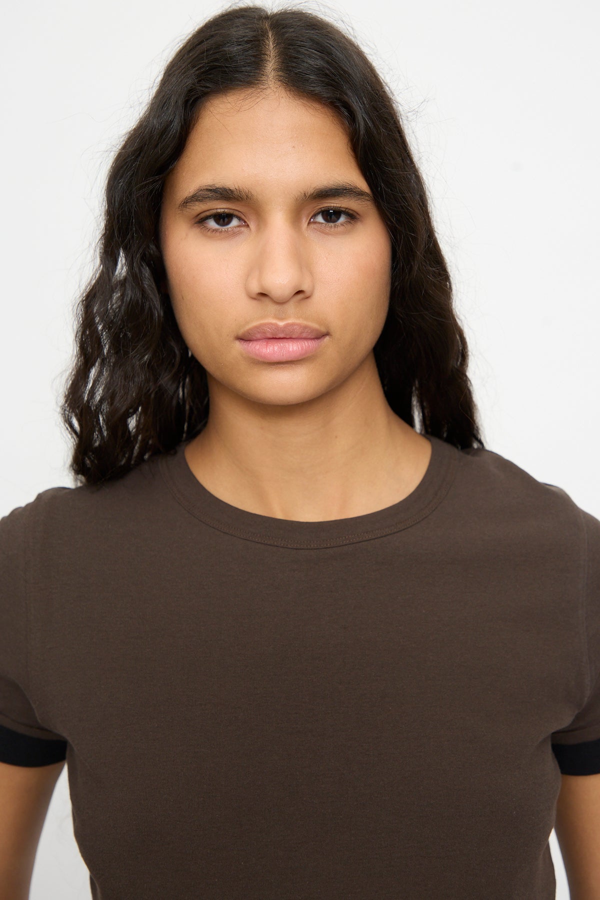 A person with long, wavy dark hair wears the B Sides Double Tee in Walnut and Black, standing against a white background.