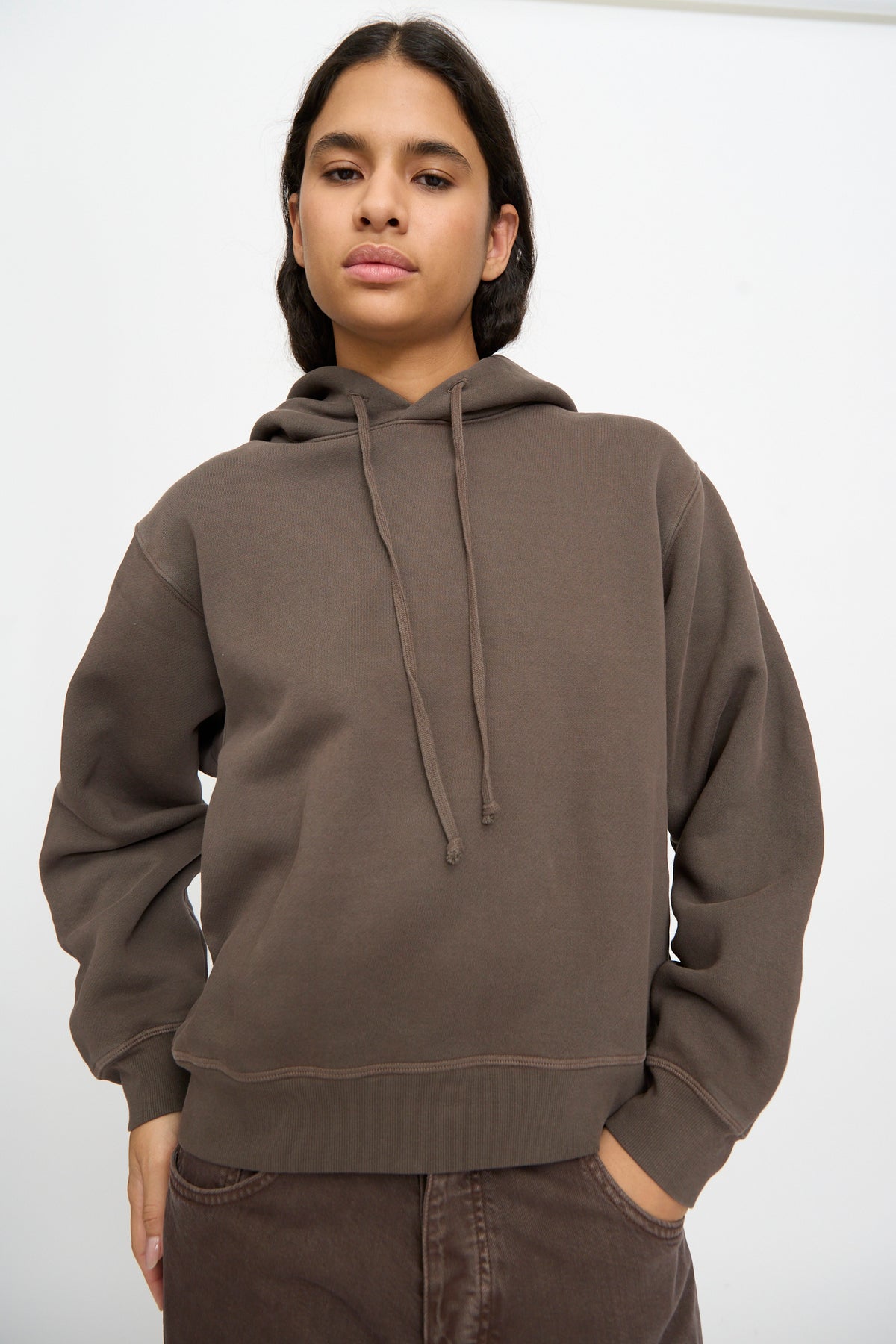 Model wears the B Sides Hoodie in Vintage Saddle Overdye, pairing it with matching pants and posing against a plain white background, one hand in pocket.