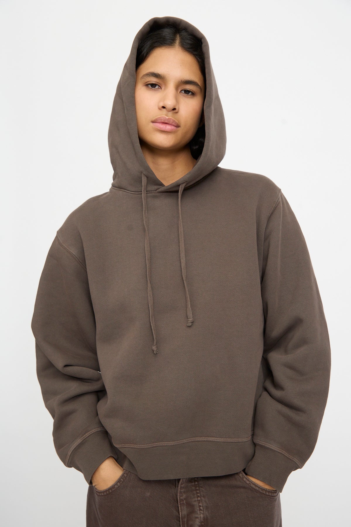Person wearing the B Sides Hoodie in Vintage Saddle Overdye, hands in pockets, facing forward against a plain light background.