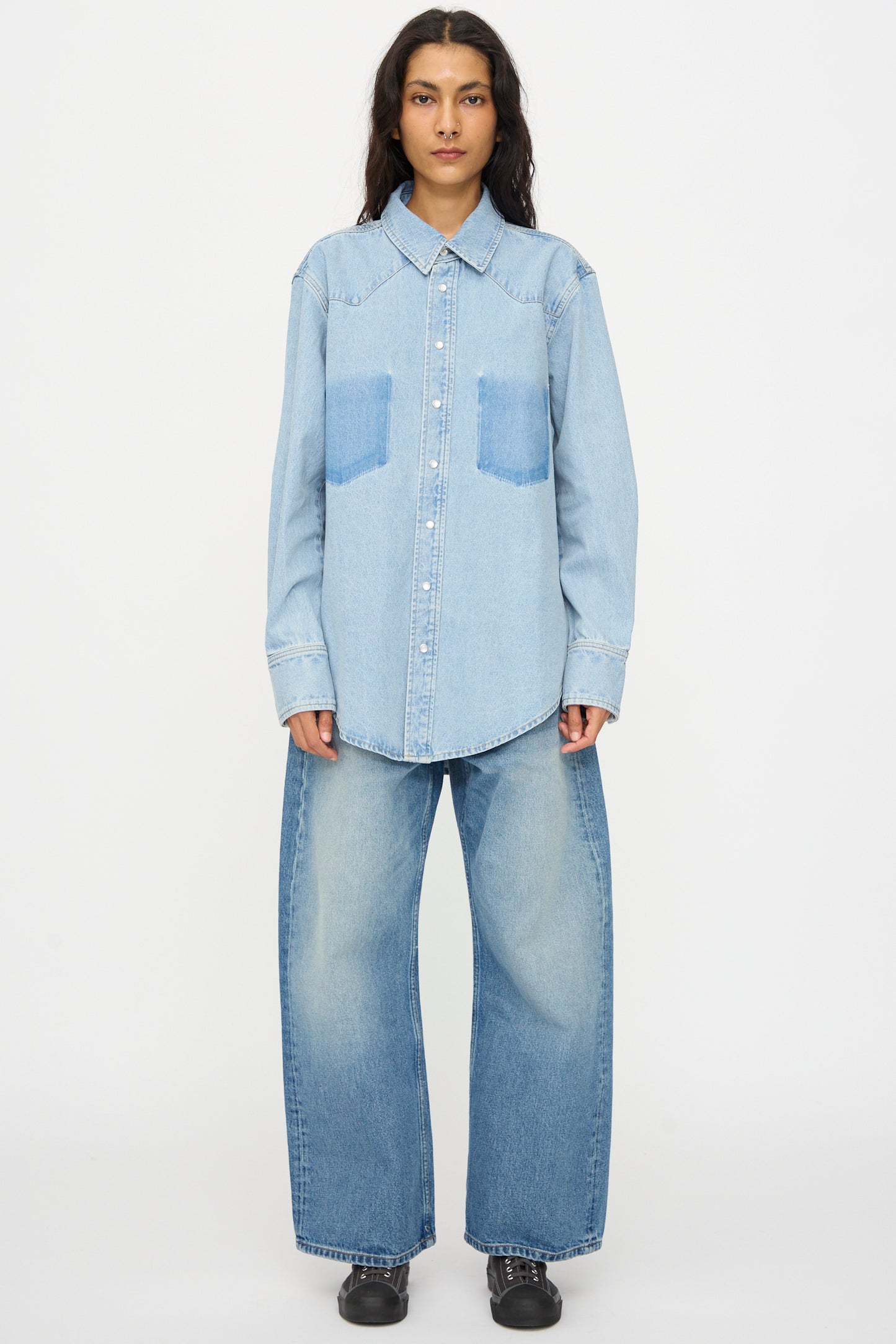 A person faces forward wearing the B Sides Liv Western Shirt in Park Wash and wide-leg jeans with black shoes against a plain white background.