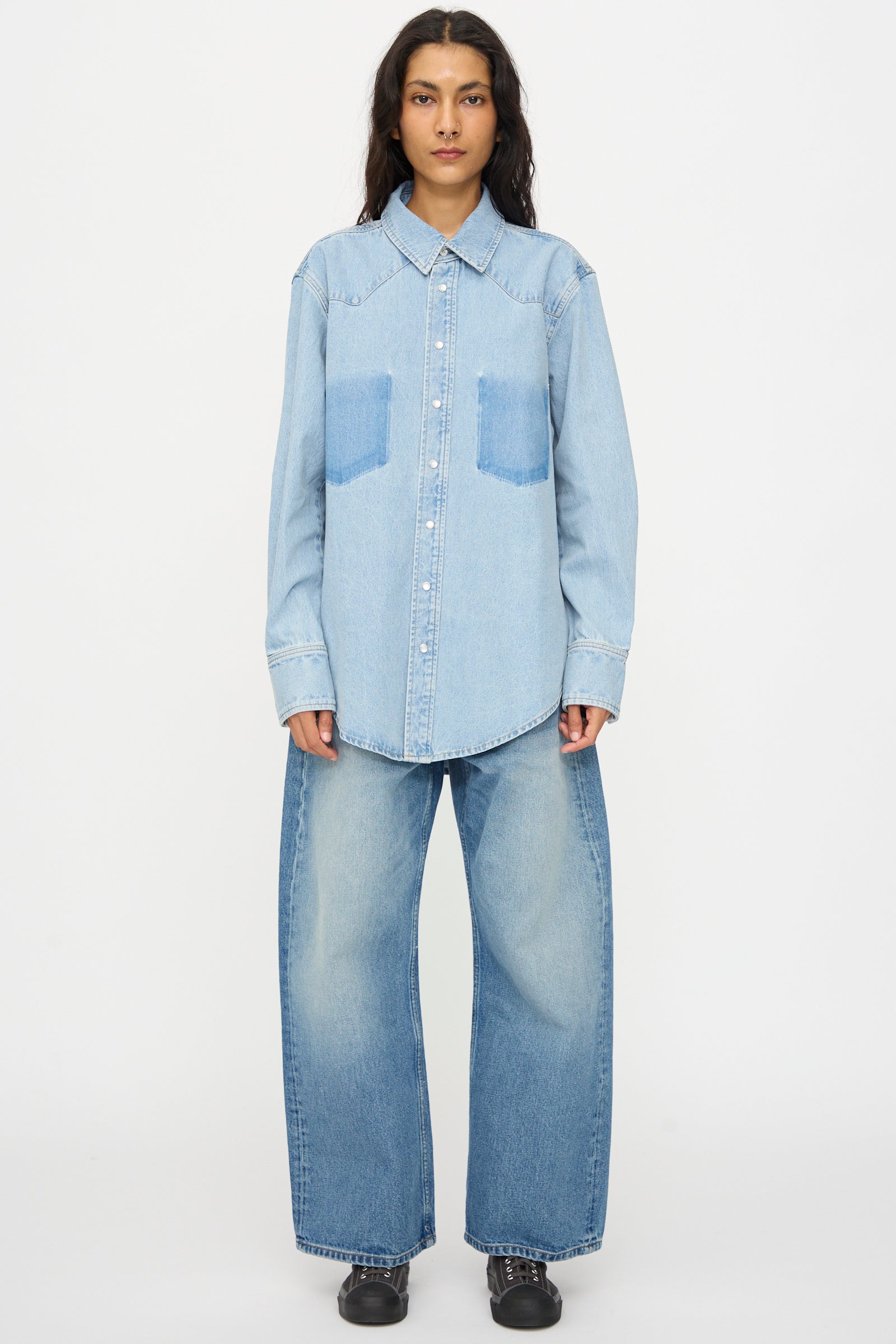 A person faces forward wearing the B Sides Liv Western Shirt in Park Wash and wide-leg jeans with black shoes against a plain white background.