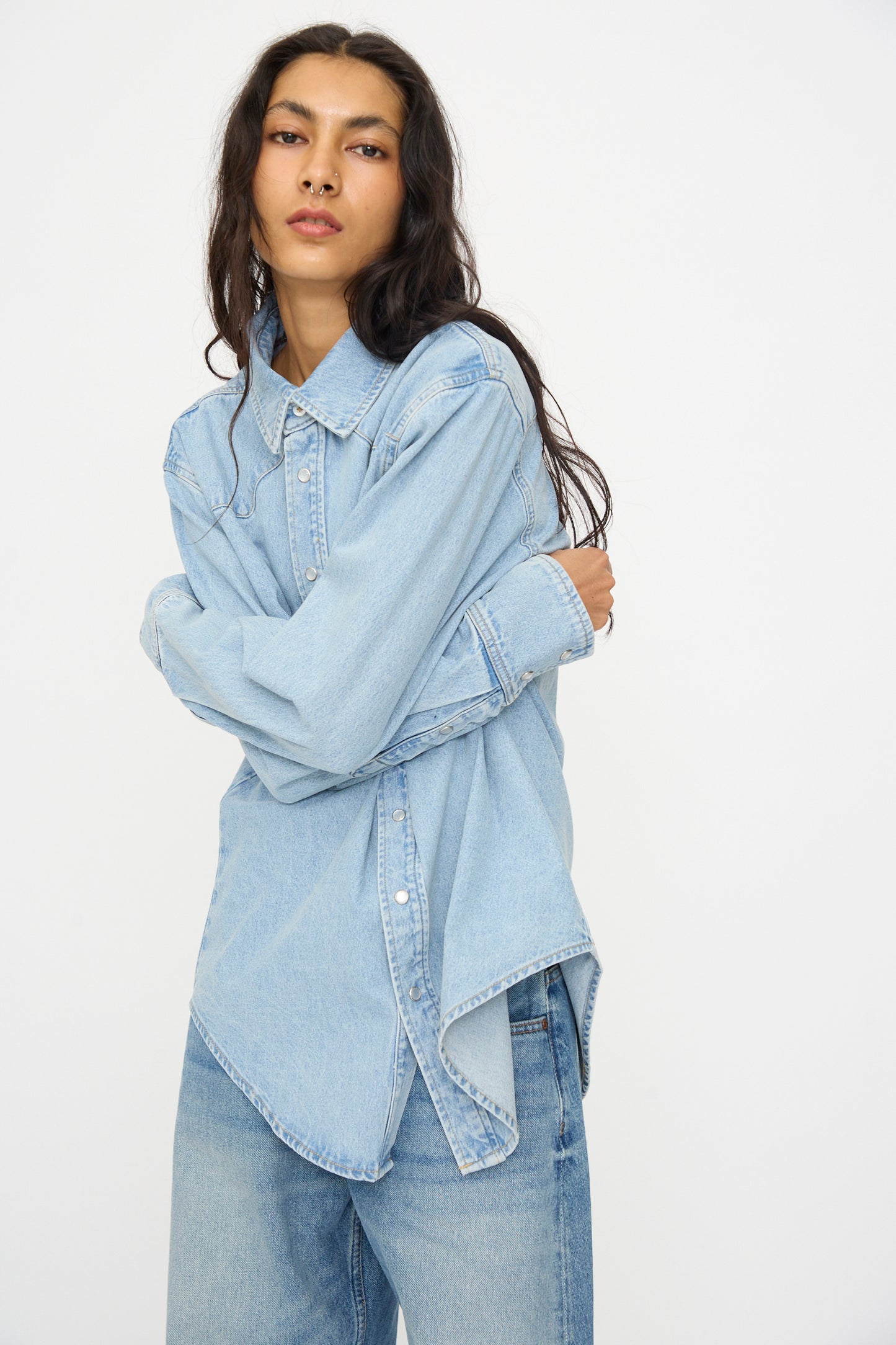 A person with long dark hair models the B Sides Liv Western Shirt in Park Wash, styled with jeans and arms crossed, set against a plain white background.
