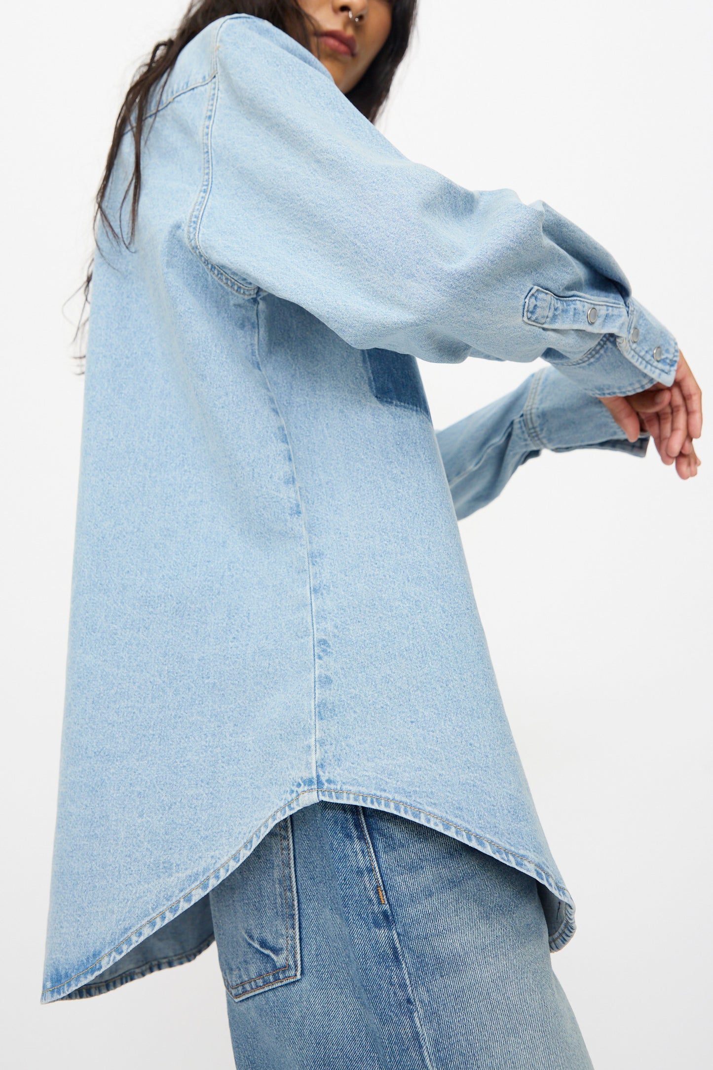 A person wears the B Sides Liv Western Shirt in Park Wash with jeans, standing with arms slightly bent, shown from a low angle against a plain background.