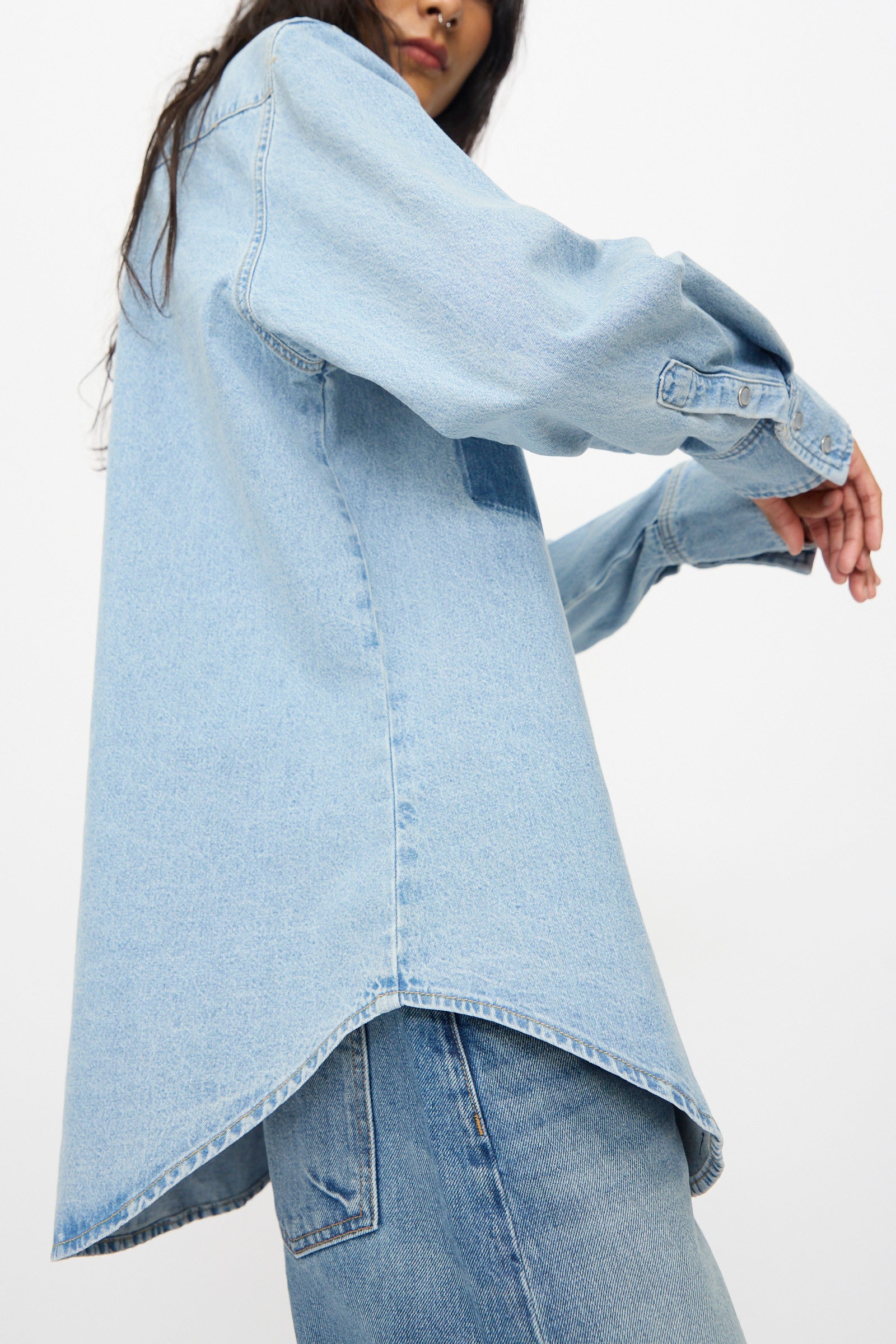 A person wears the B Sides Liv Western Shirt in Park Wash with jeans, standing with arms slightly bent, shown from a low angle against a plain background.
