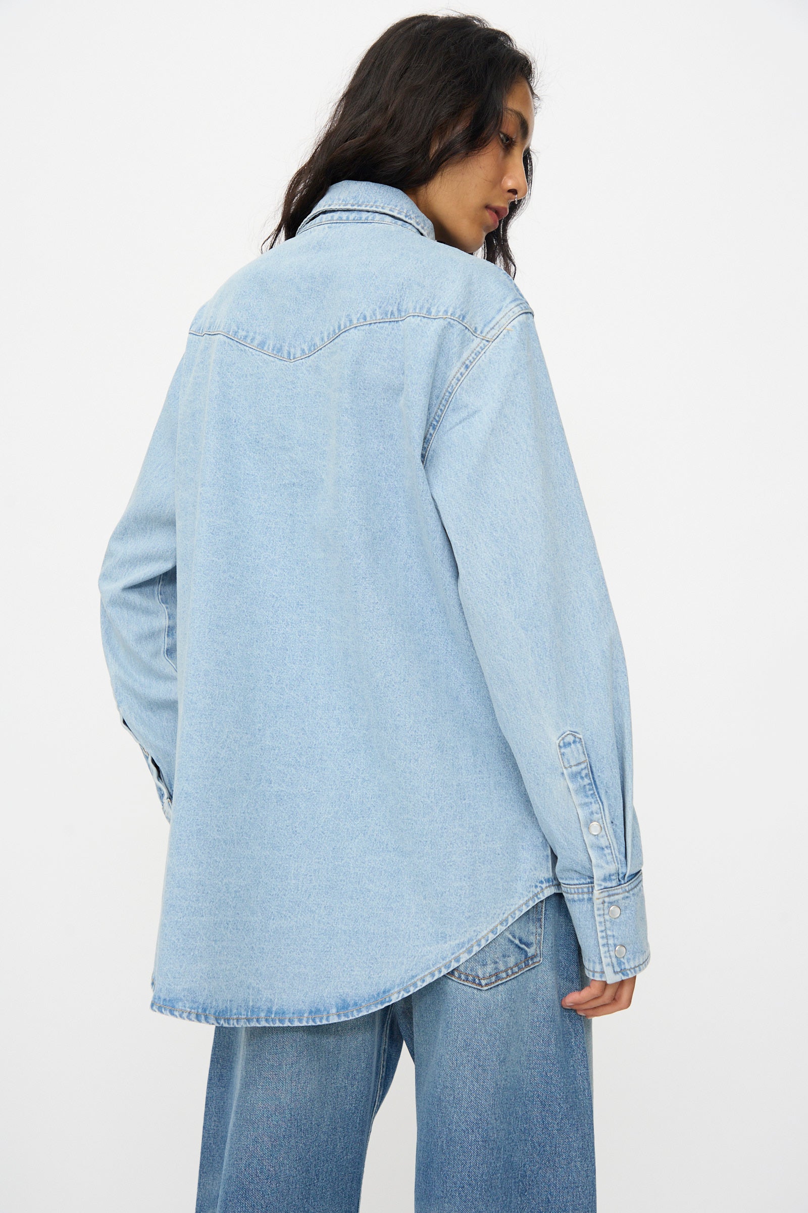 A person wearing the B Sides Liv Western Shirt in Park Wash and jeans stands with their back to the camera against a plain white background.