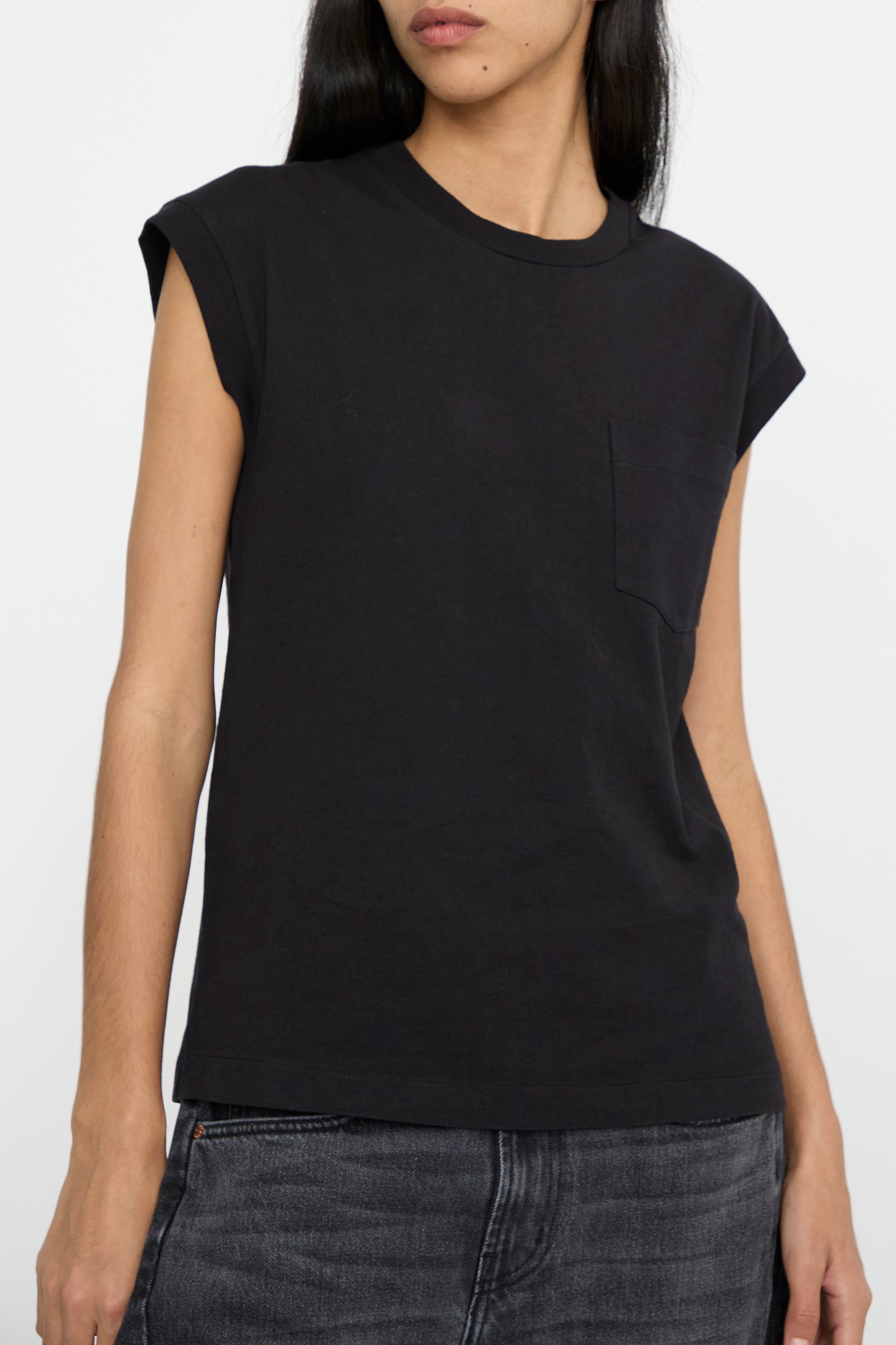 An image of a person's torso wearing the Pocket Tank in Stil Black by B Sides and dark jeans stands against a plain background.