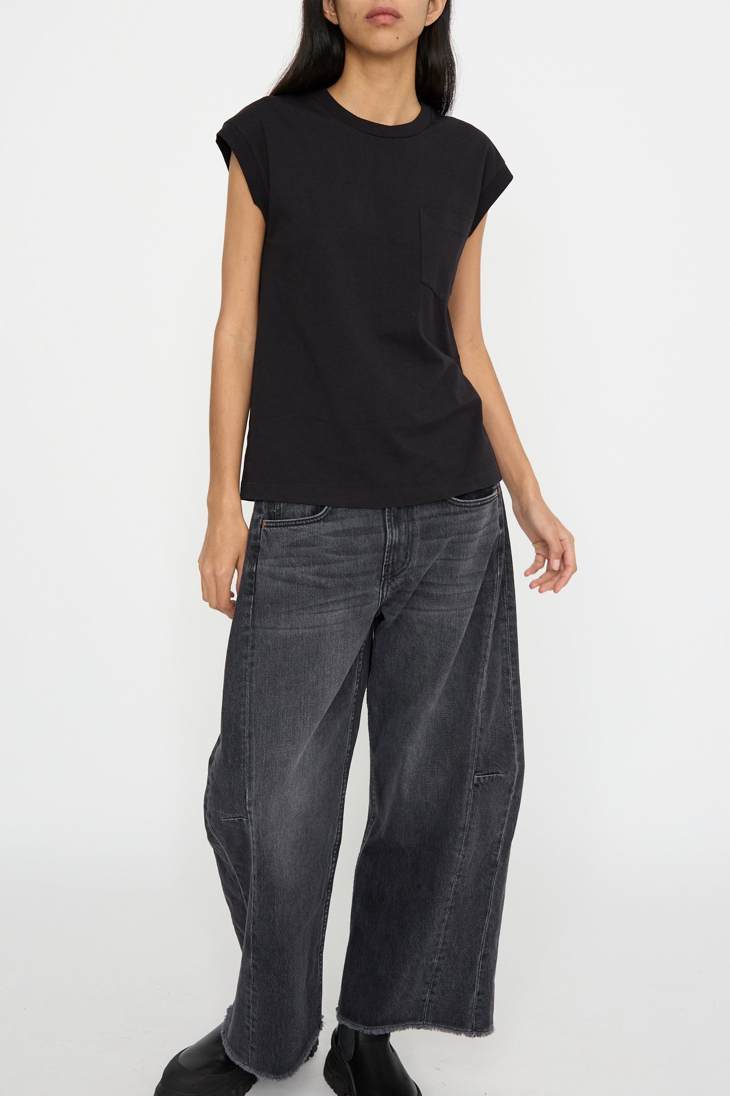 A person wearing the B Sides Pocket Tank in Stil Black and wide-leg black jeans with a single front pocket stands against a plain white background.