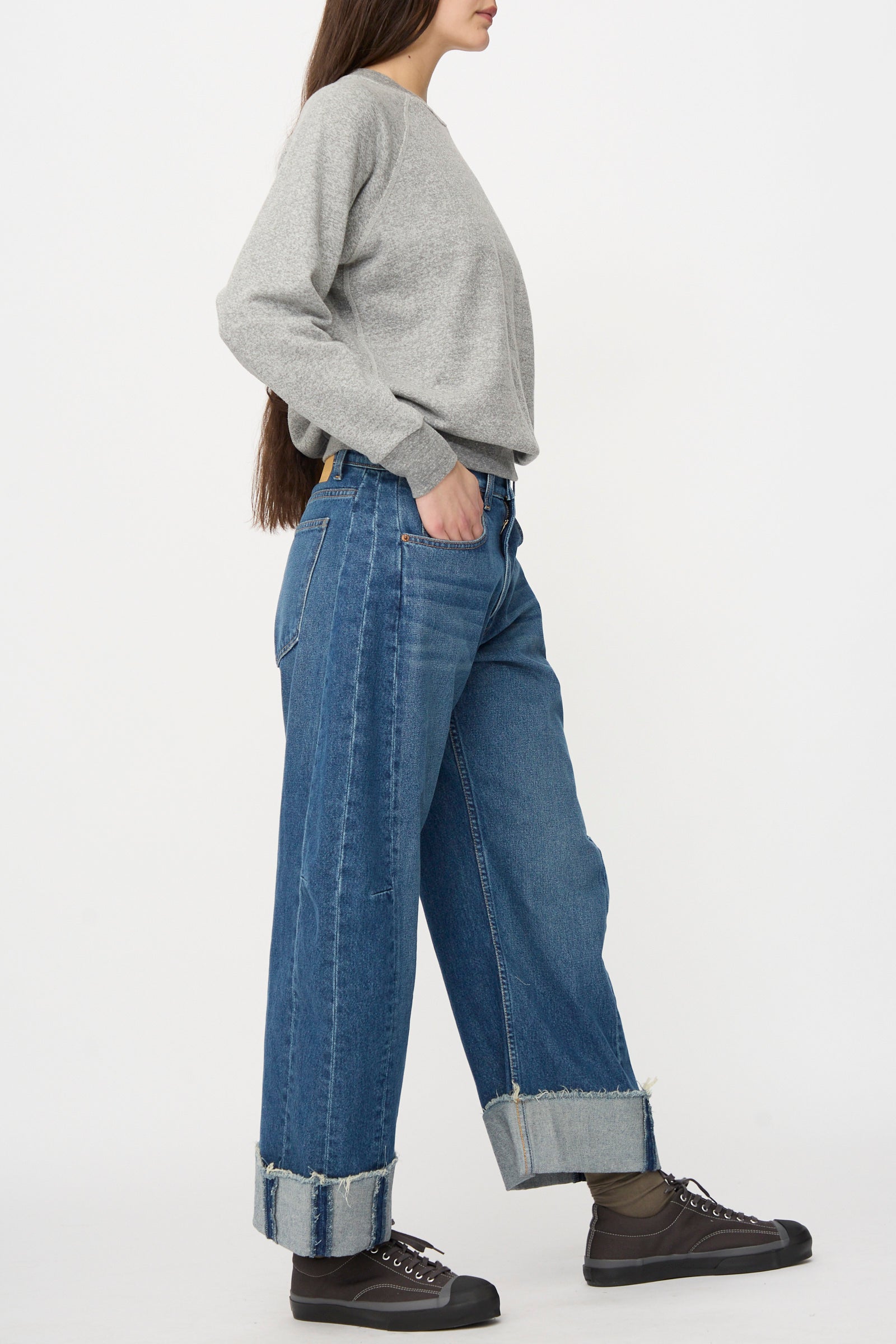 Person wearing a grey long-sleeve shirt, brown socks, black sneakers, and B Sides Relaxed Cuffed Lasso Jean in Cate Wash, standing against a plain white background.