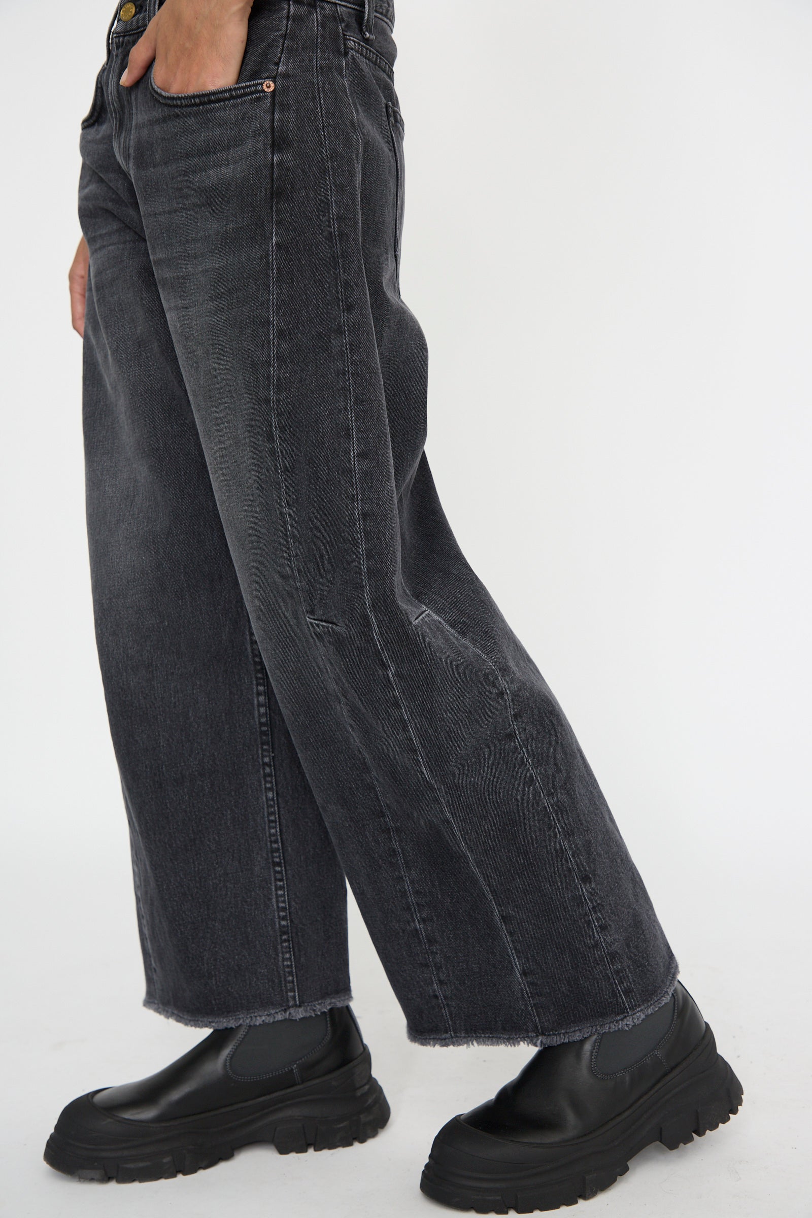 A person is wearing the Relaxed Lasso Jean in Stil Black by B Sides, crafted from 100% cotton, paired with black shoes against a white background.