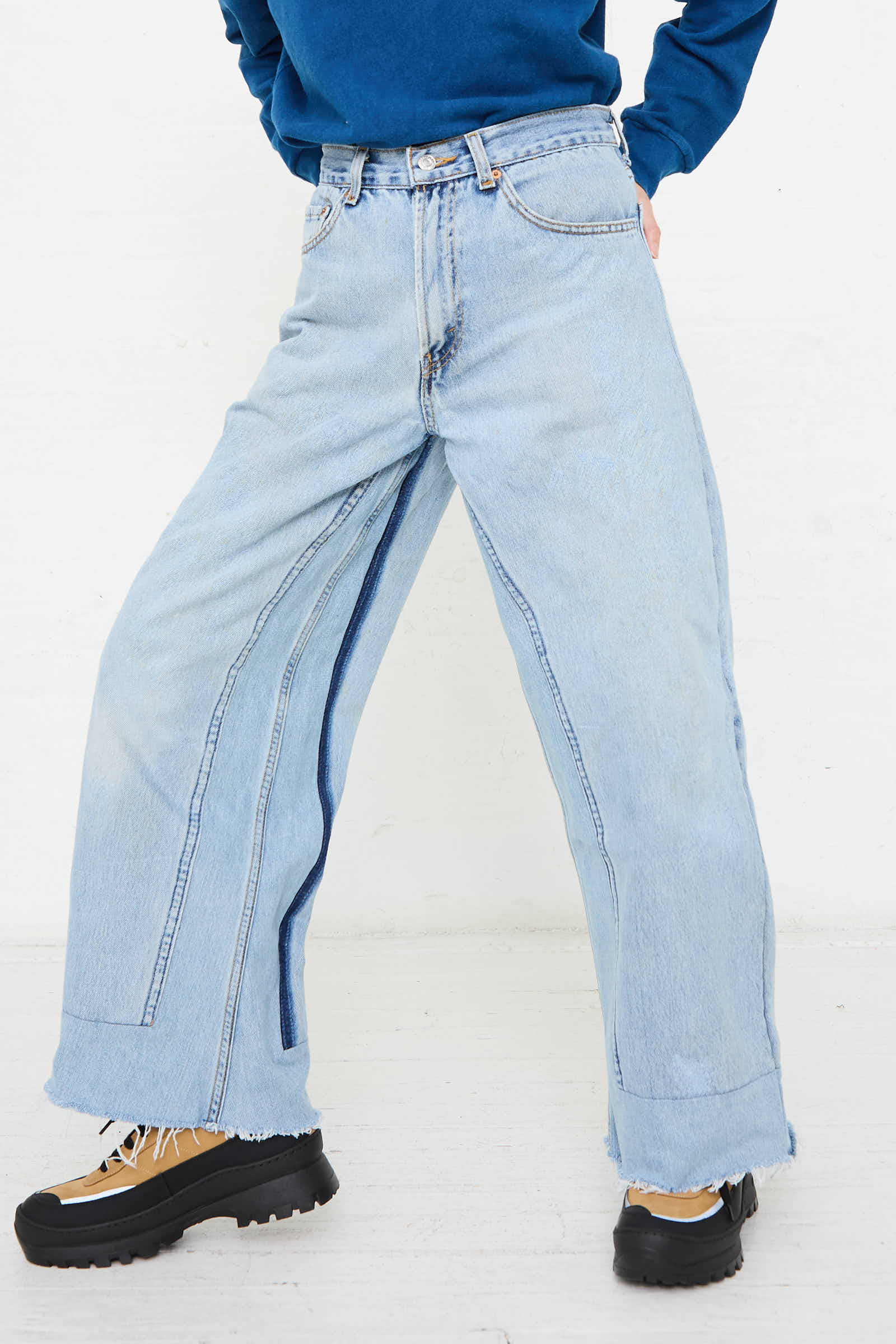 Person wearing B Sides Reworked Culotte in Vintage Indigo, paired with a blue shirt and brown hiking boots, standing against a white background.