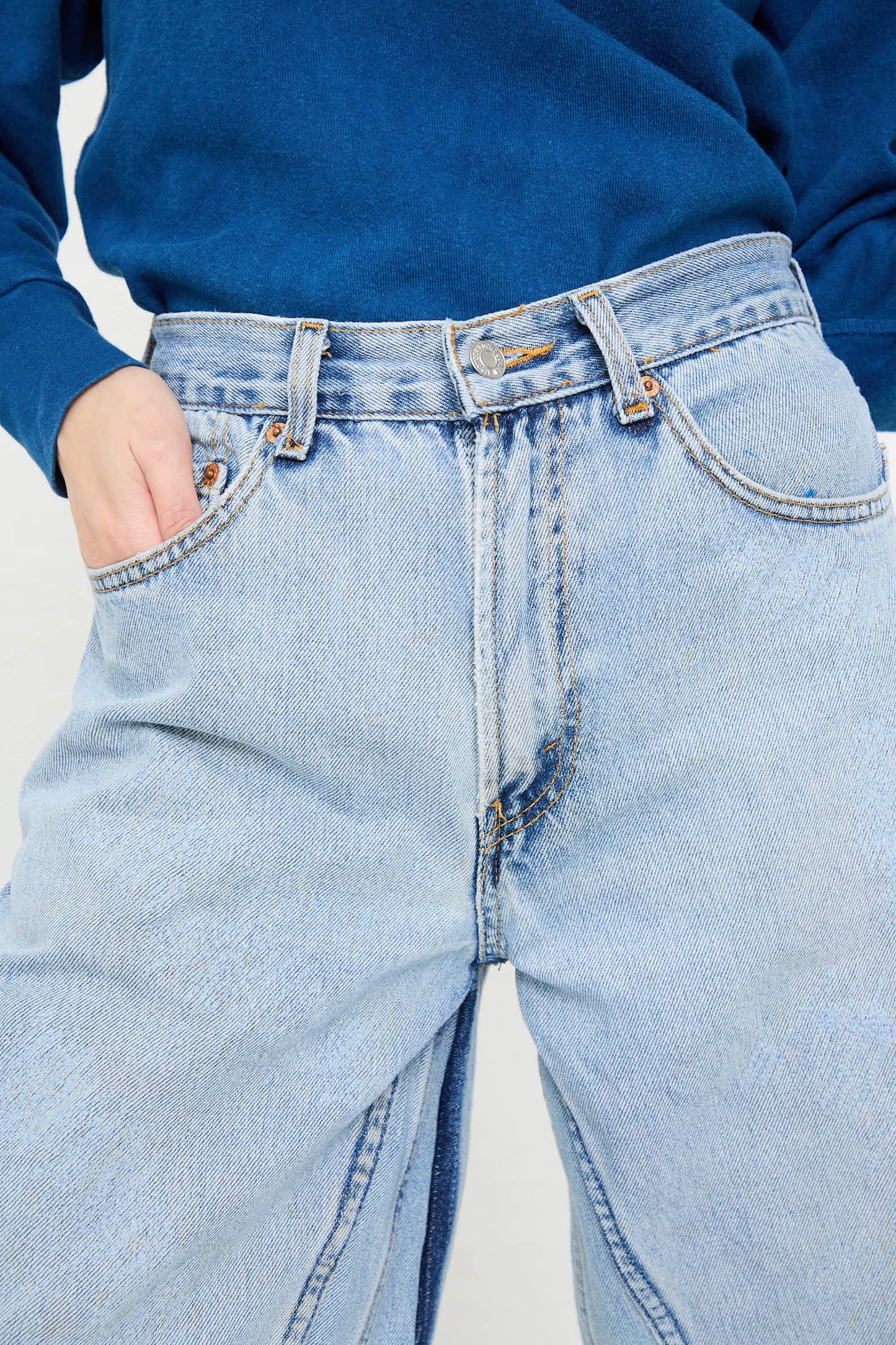 Close-up of a person wearing high-waisted Reworked Culotte in Vintage Indigo from B Sides and a blue top. Their left hand is in their pocket.