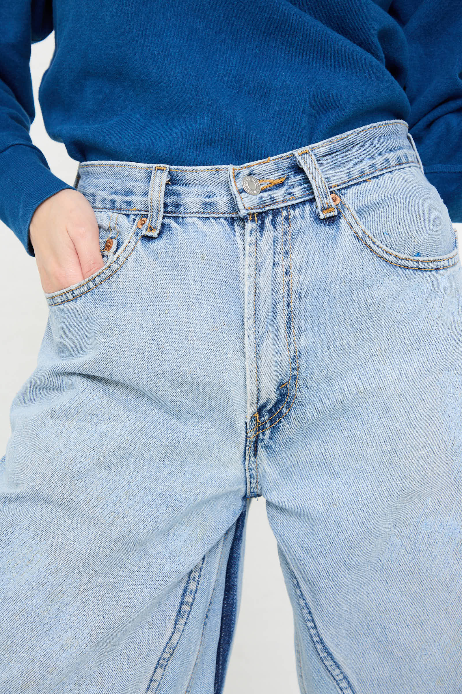 Close-up of a person wearing high-waisted Reworked Culotte in Vintage Indigo from B Sides and a blue top. Their left hand is in their pocket.